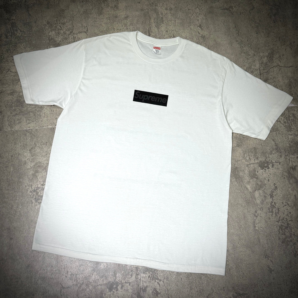 Supreme Seoul Box Logo Tee FW26 - White displayed on a textured surface, featuring a black box logo.