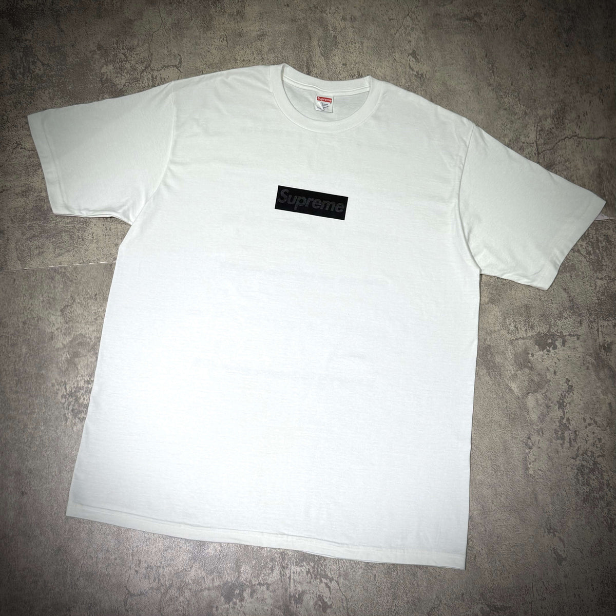 Supreme Seoul Box Logo Tee FW26 - White displayed on a textured surface, featuring a black box logo.
