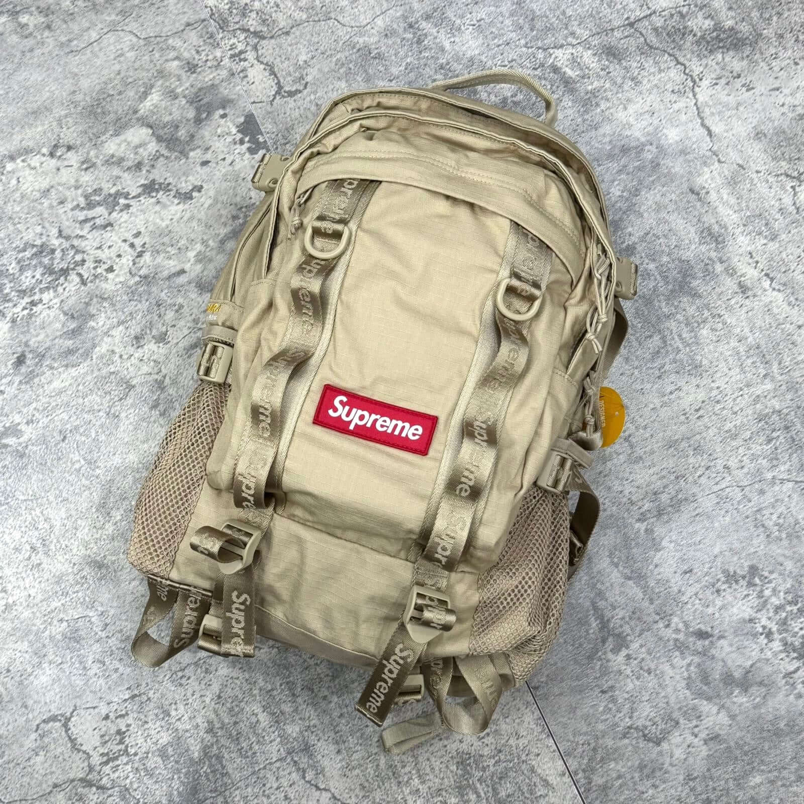 Supreme Backpack SS26 in beige color with red logo and mesh pockets, showcasing water resistant Cordura® material.