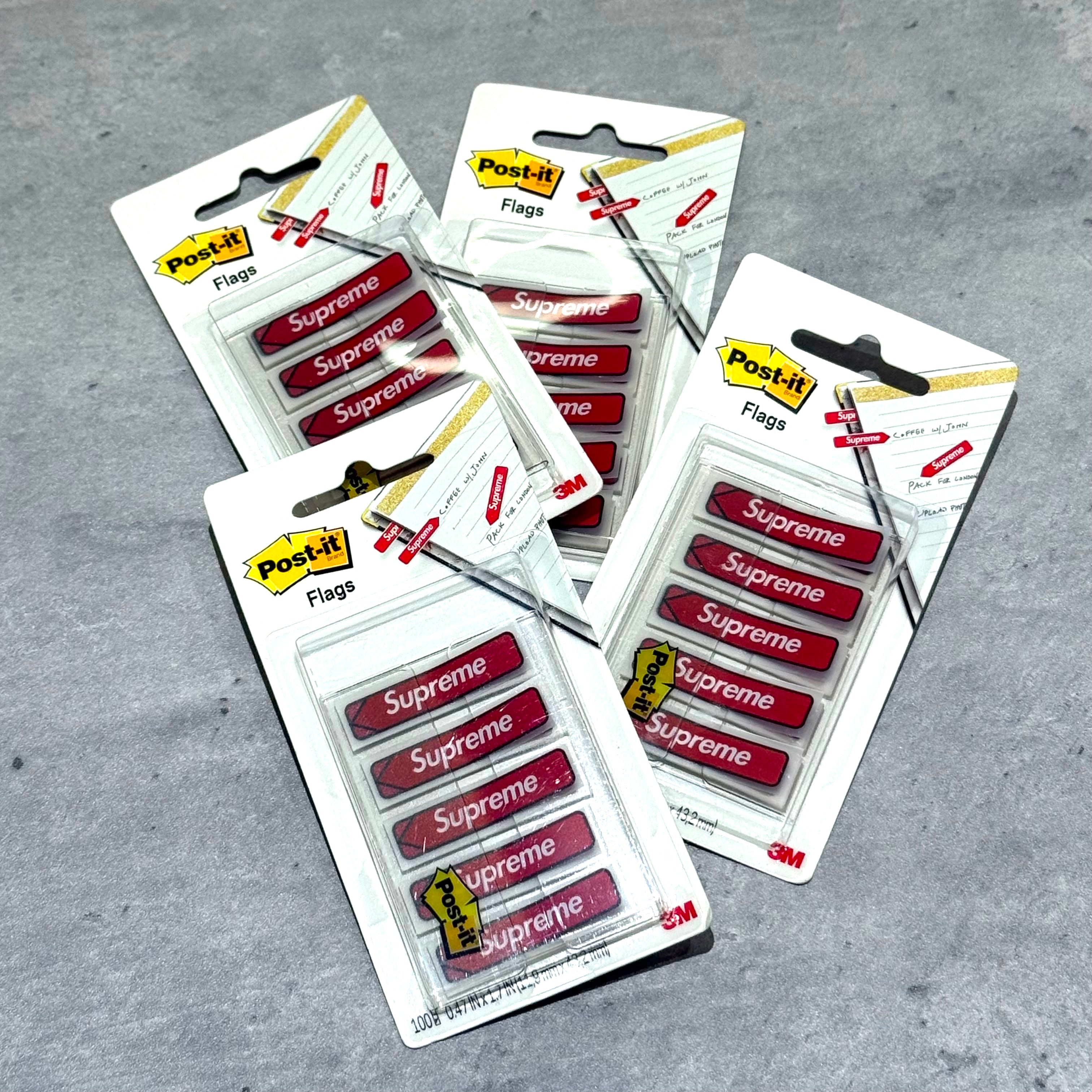 Supreme Post-it Flags - Red packages displayed on a gray surface showcasing their design and branding.