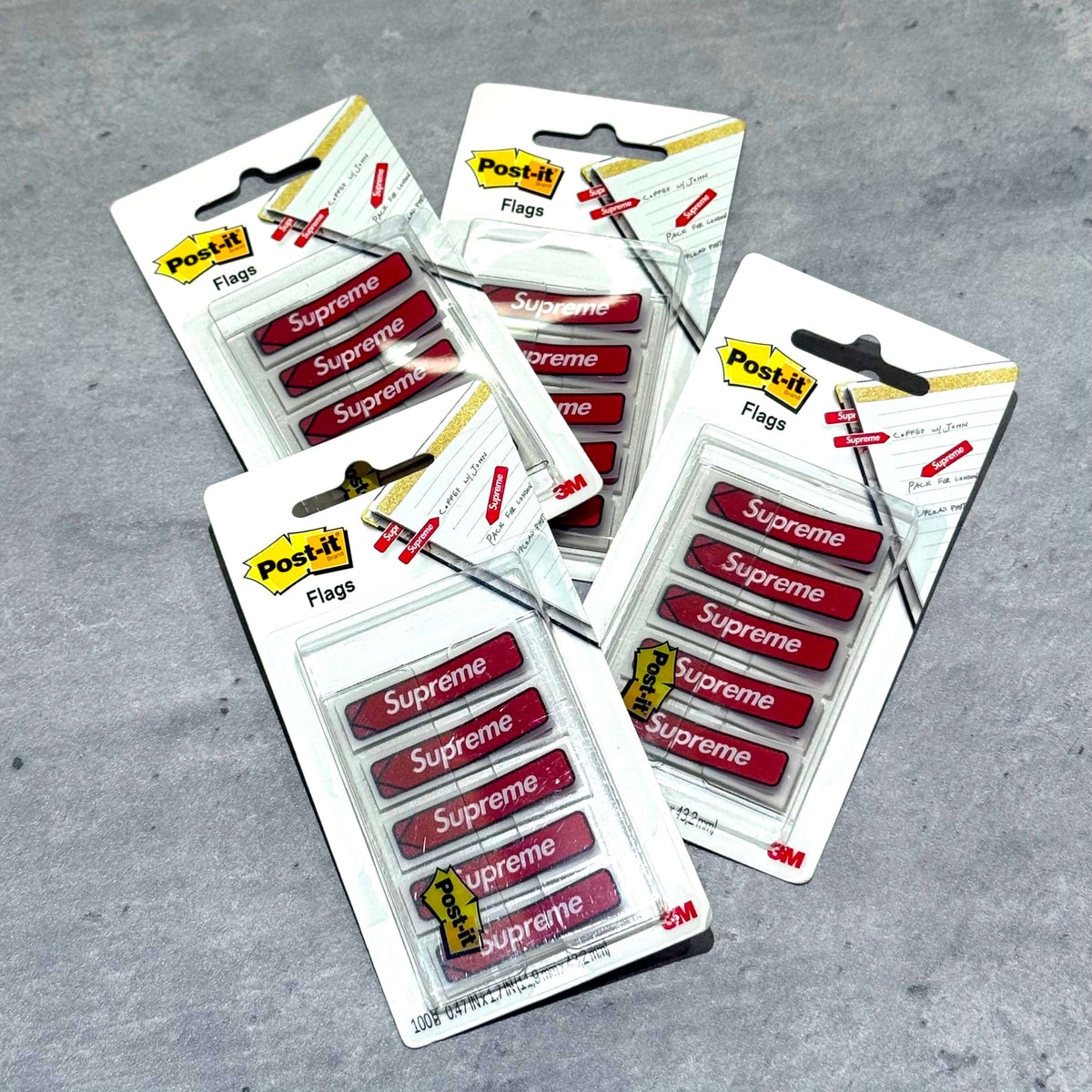 Supreme Post-it Flags - Red packages displayed on a gray surface showcasing their design and branding.