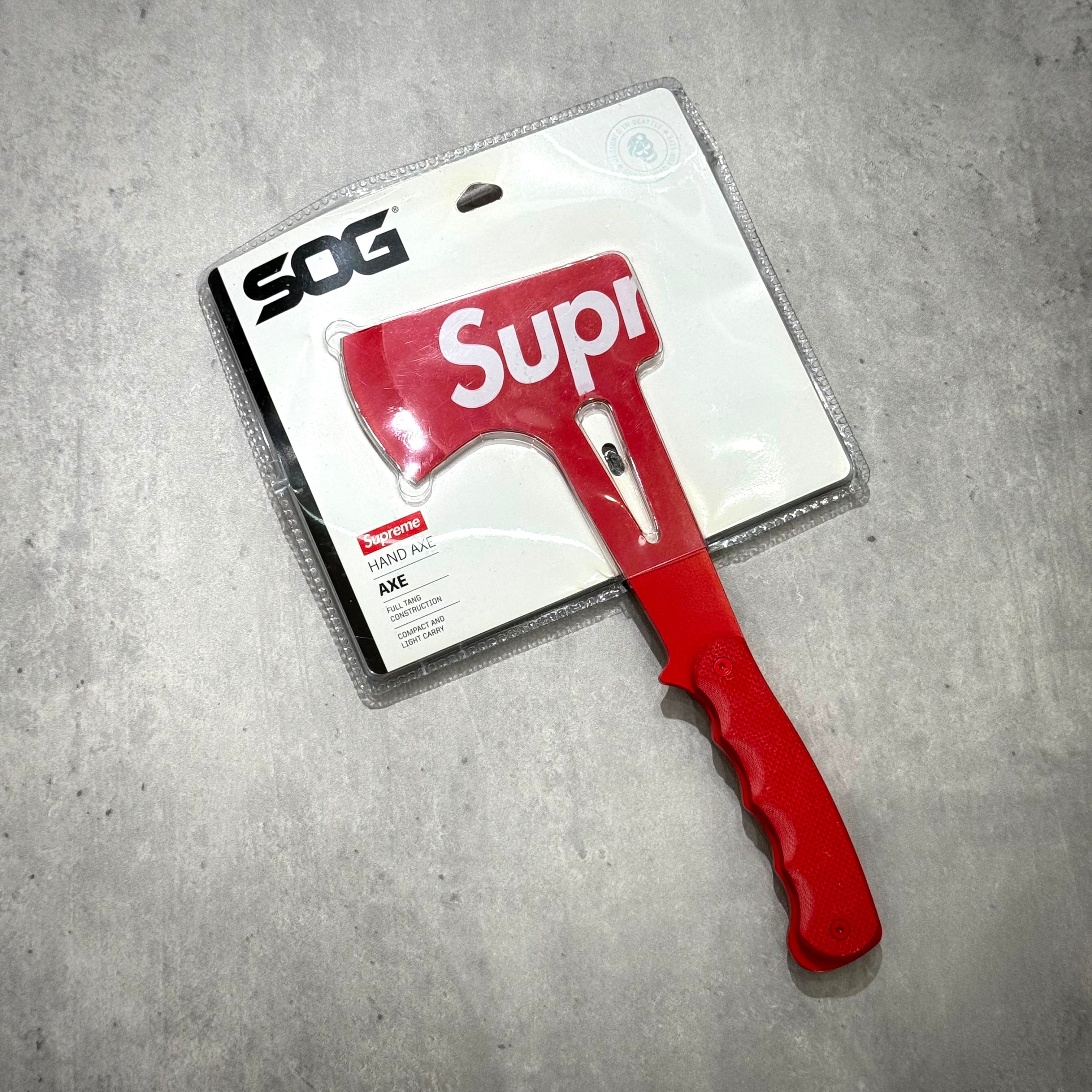 Supreme SOG Hand Axe - Red in packaging with distinct logo and bright red handle.