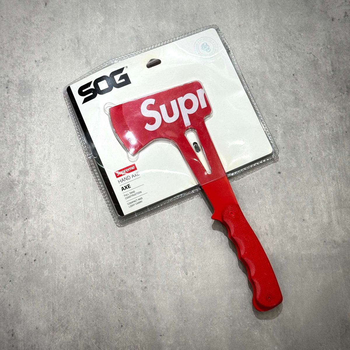 Supreme SOG Hand Axe - Red in packaging with distinct logo and bright red handle.