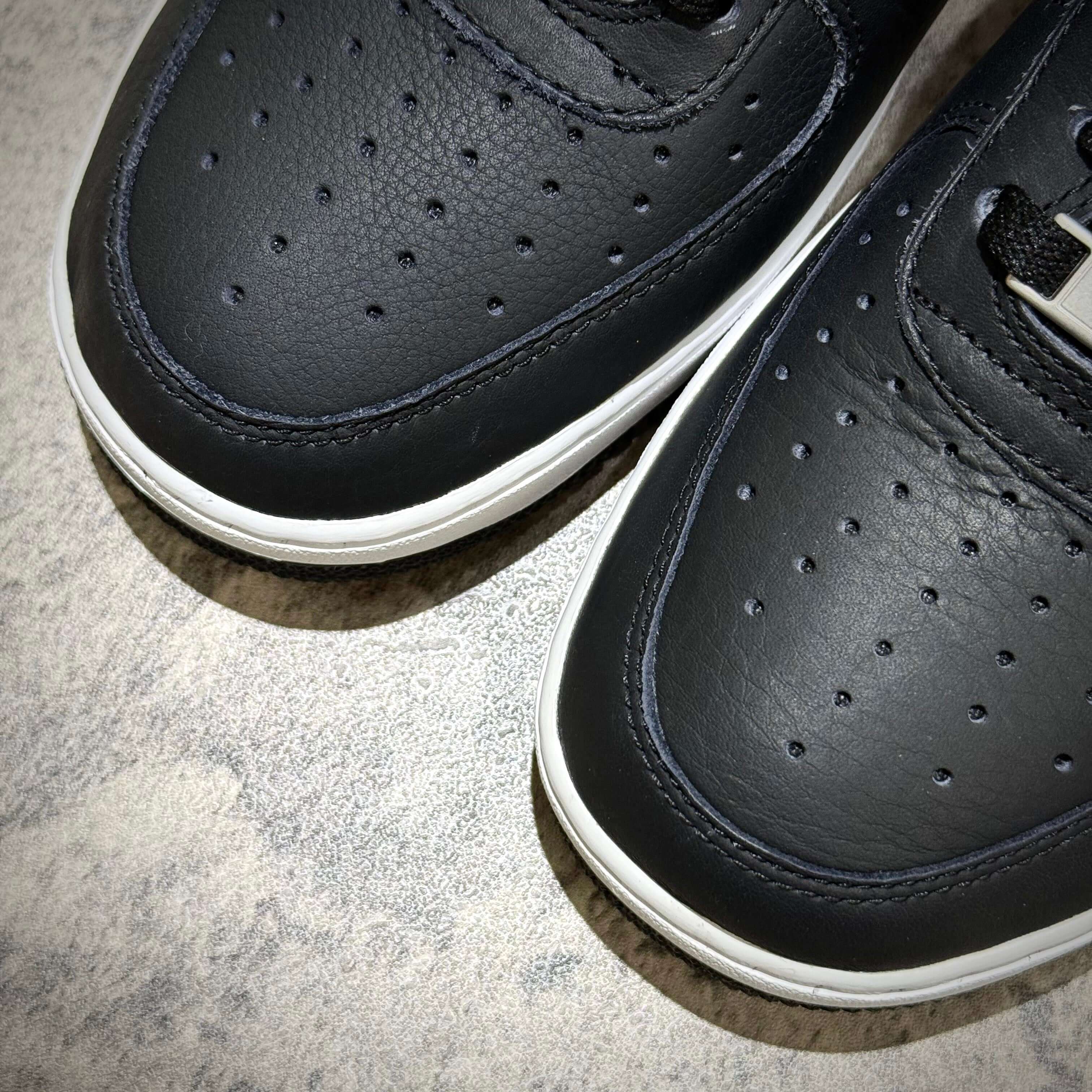 Close-up of Supreme x Comme des Garçons x Nike Split Logo Air Force 1 Low sneakers showcasing black leather upper.