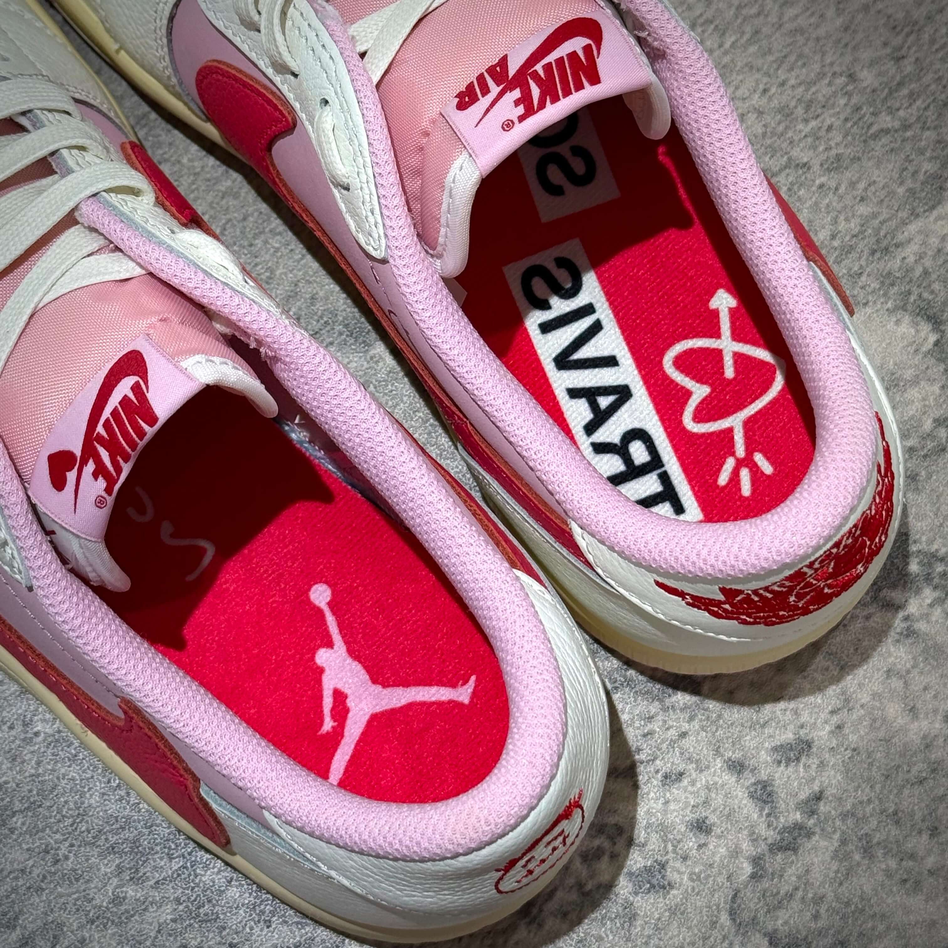 Travis Scott × Nike Air Jordan 1 Retro Low SP Tropical Pink sneakers featuring pink and red insoles with Travis branding.