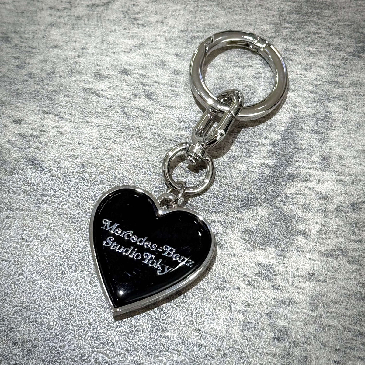 VERDY x Mercedes-Benz STUDIO TOKYO Keyring in heart shape with silver keychain on fabric background.