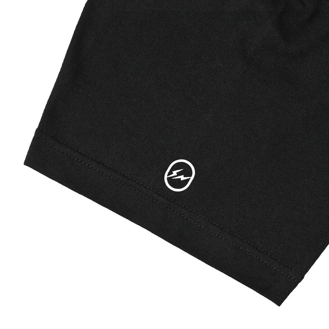 Close-up of the hem of the Artist Proof x Fragment x nonnative Innovaten Tee featuring a distinctive logo detail.