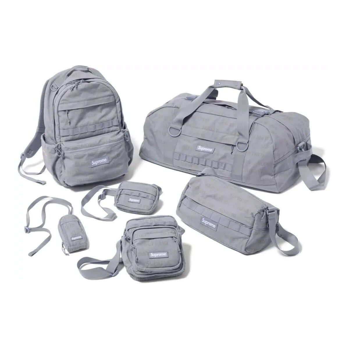 A collection of gray Supreme bags including a backpack, duffel bag, and various smaller bags, featuring the Supreme Bag FW26.