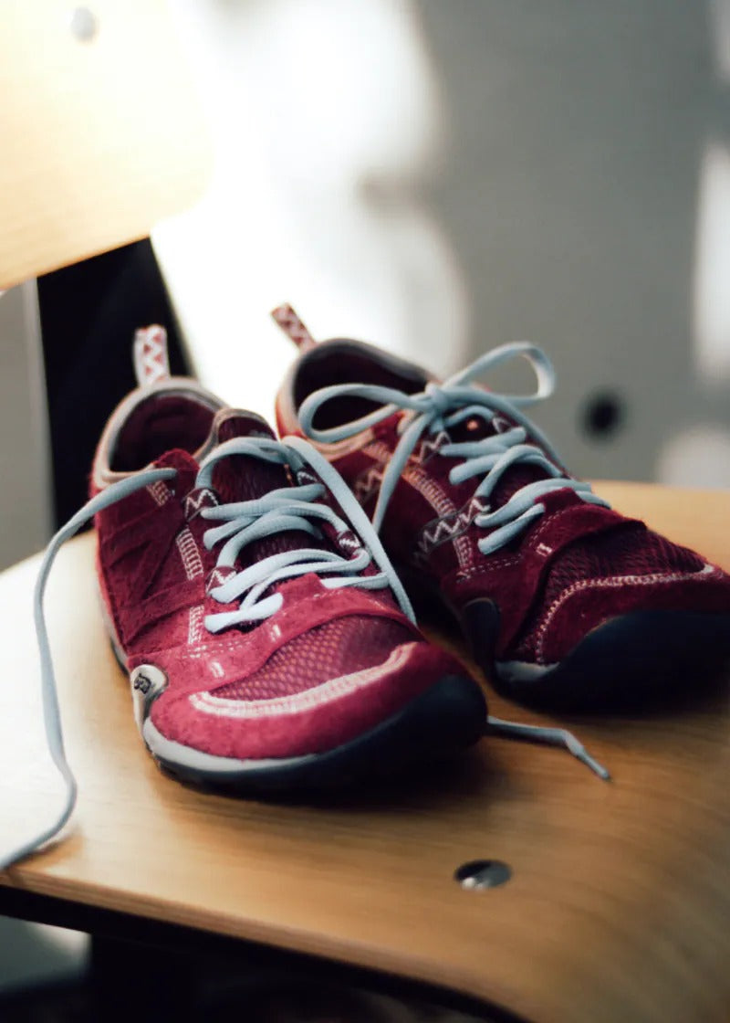 SUNLOVETOUR x New Blance MT1001ND shoes in maroon color displayed on a chair with laces untied.