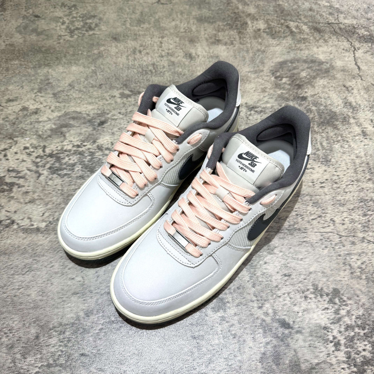 Yuto Horigome x Nike SB Air Force 1 Low IO8439-100 with light grey color and pink laces on a textured surface.