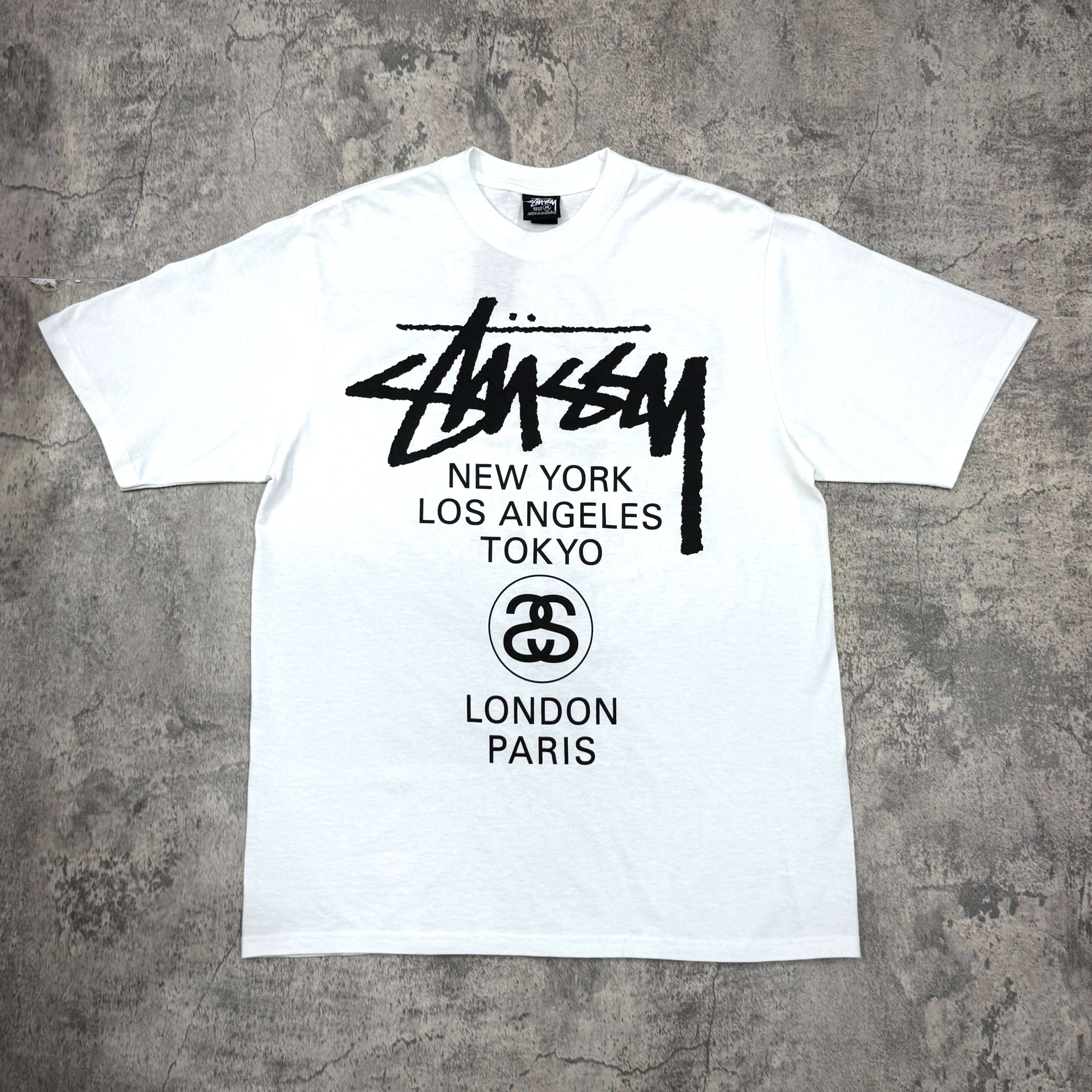 現貨 Stussy World Tour Tee - Navy / Black / White,白色T恤,印有Stussy標誌及城市名稱,包括紐約、洛杉磯、東京、倫敦和巴黎