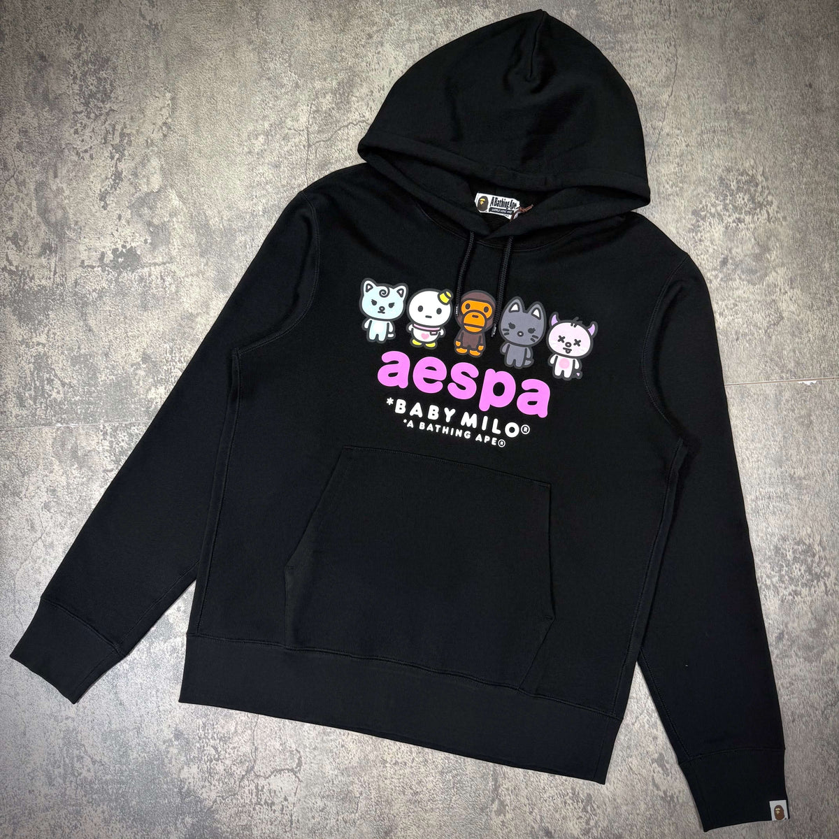 aespa x BAPE Baby Milo Pullover Hoodie featuring colorful character graphics on a black background.