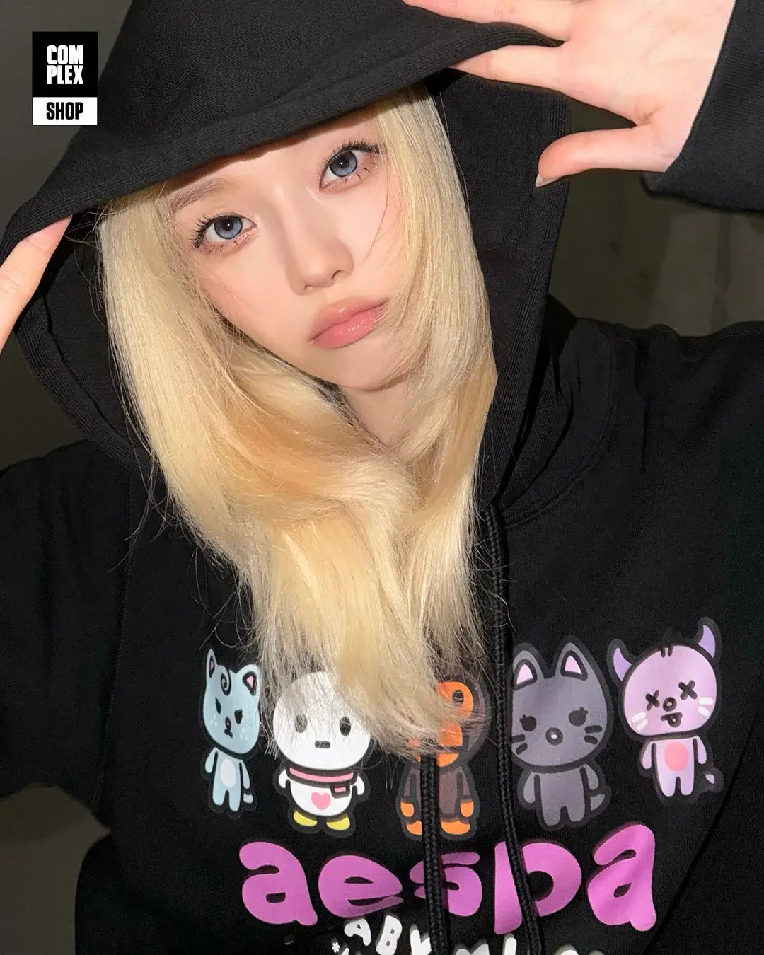 Model wearing aespa x BAPE Baby Milo Pullover Hoodie featuring colorful characters.