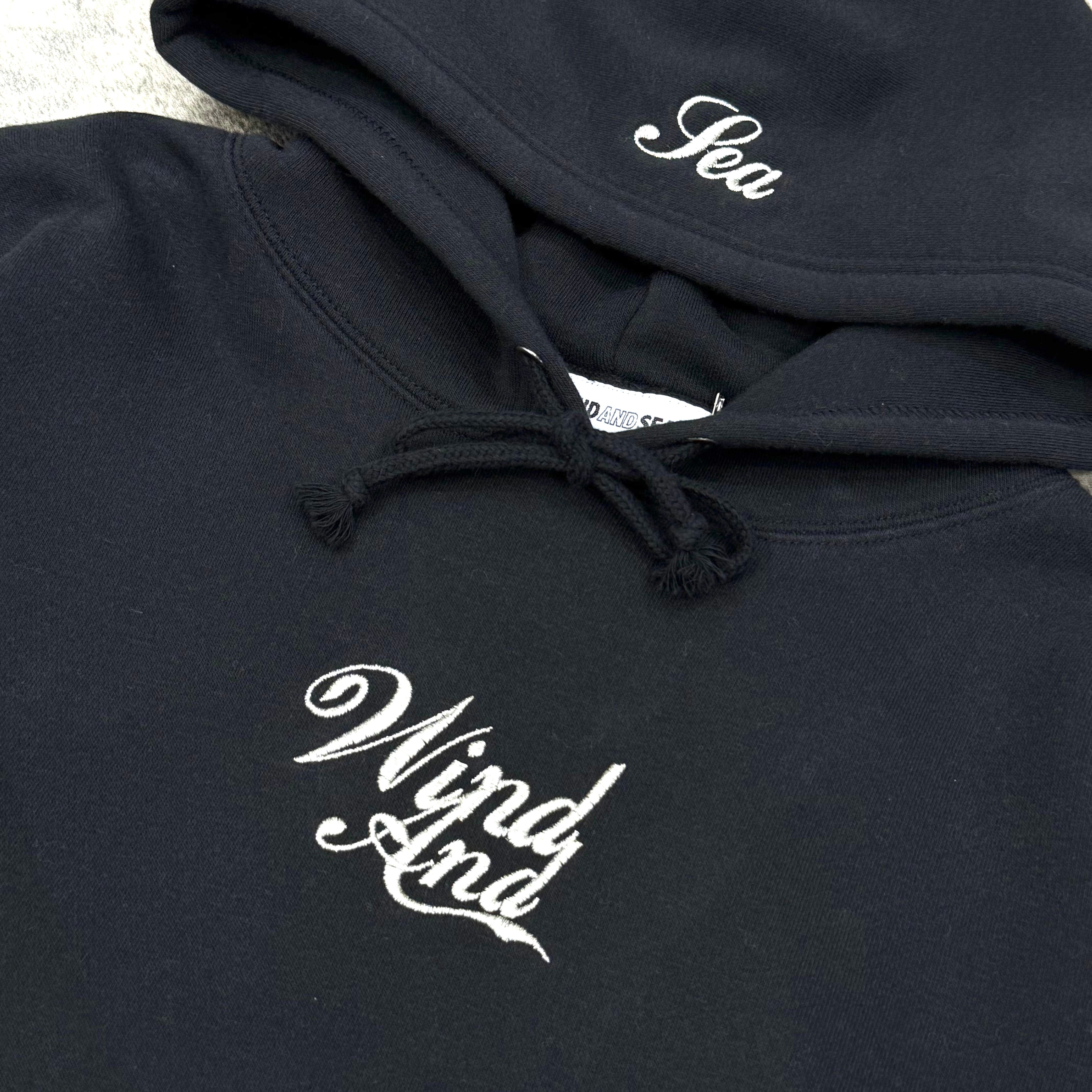 Wind And Sea Glitter Hoodie - Black / White - close-up of hood and embroidery details in black fabric.