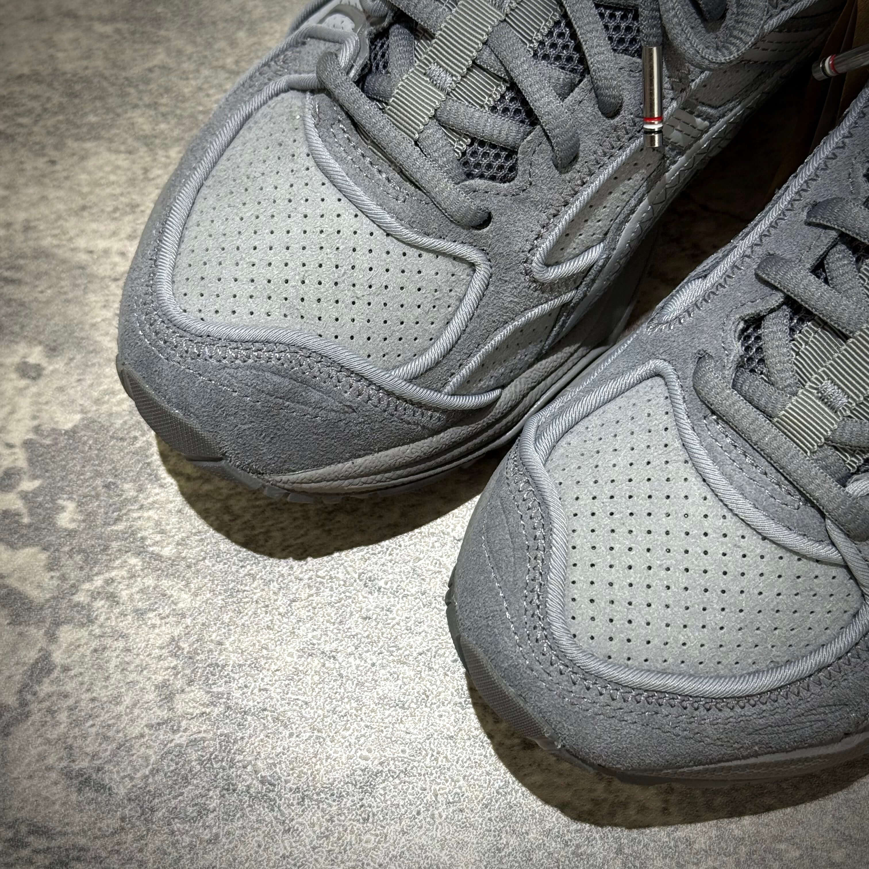 Thom Browne x Asics Gel-Kayano 14 in grey color, showcasing the textured suede and mesh upper for stylish comfort.