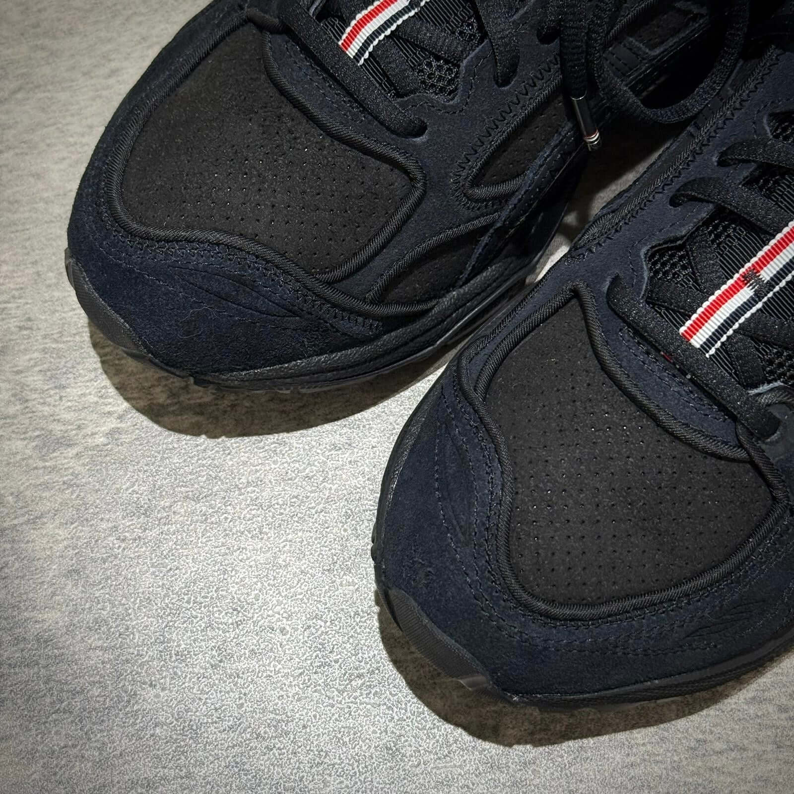 Close-up view of Thom Browne x Asics Gel-Kayano 14 - Black sneakers featuring textured details and logo.
