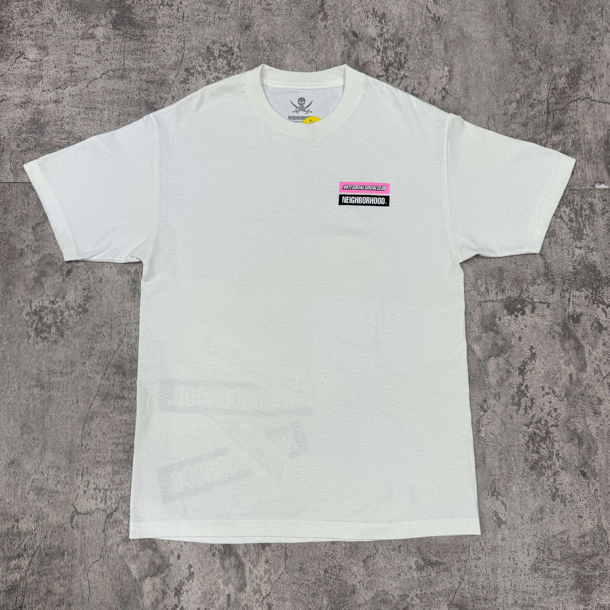 Anti Social Social Club x Neighborhood Stuck On You Tee displayed on a textured surface.