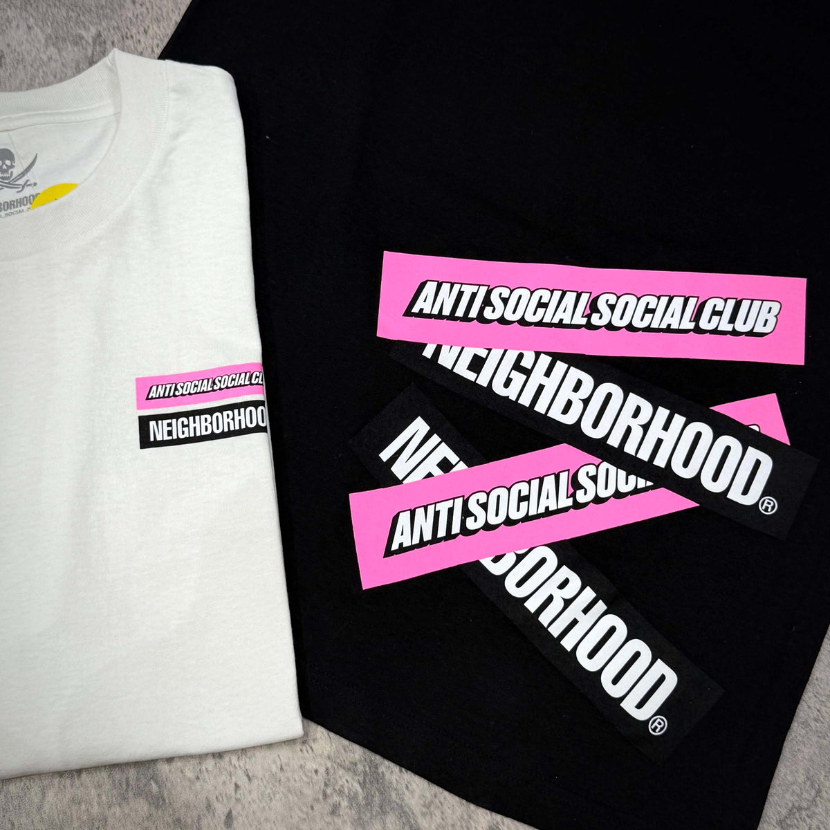 Anti Social Social Club x Neighborhood Stuck On You Tee on display, featuring bold logo designs in pink and black.