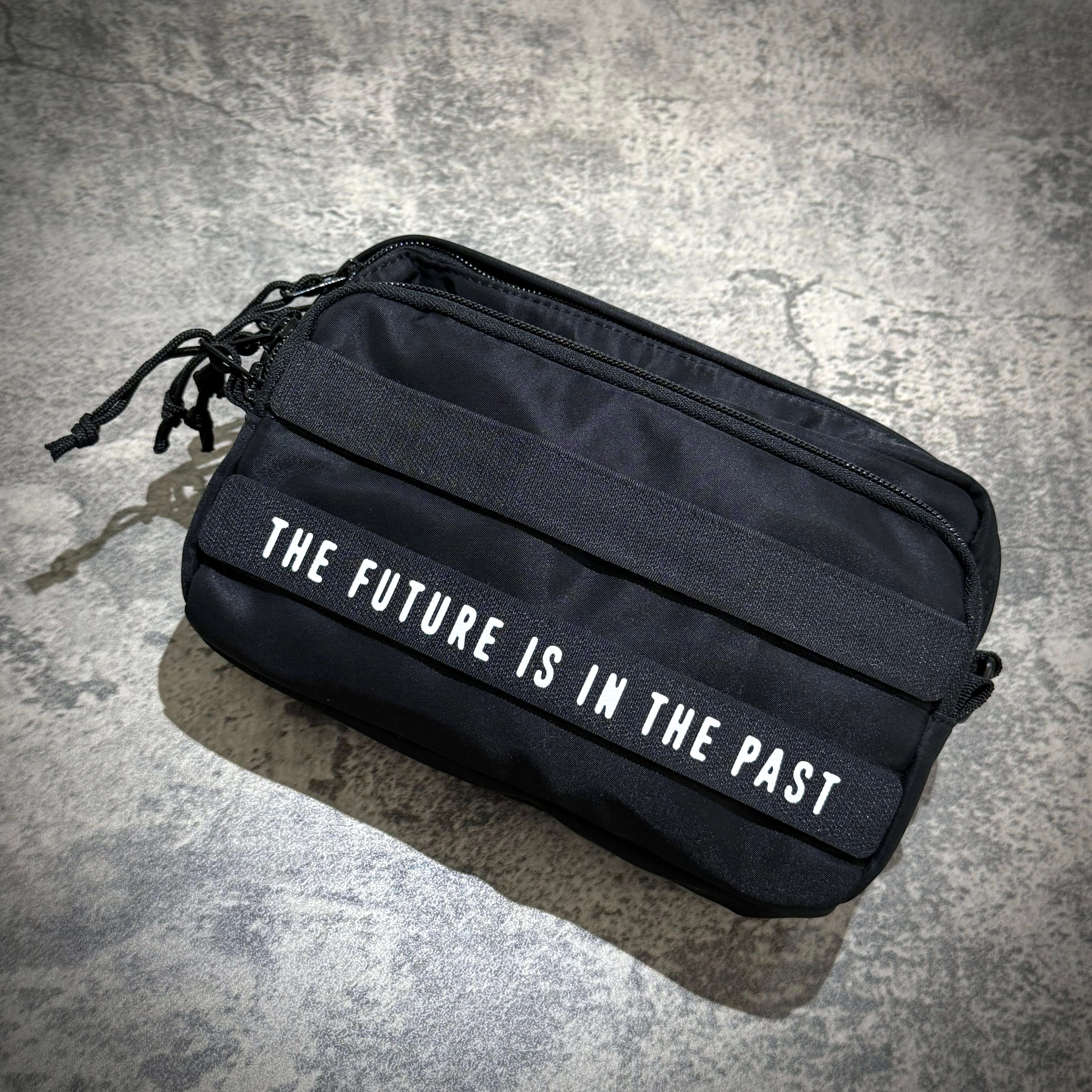 Black Human Made Military Pouch featuring text 'THE FUTURE IS IN THE PAST' on the front.