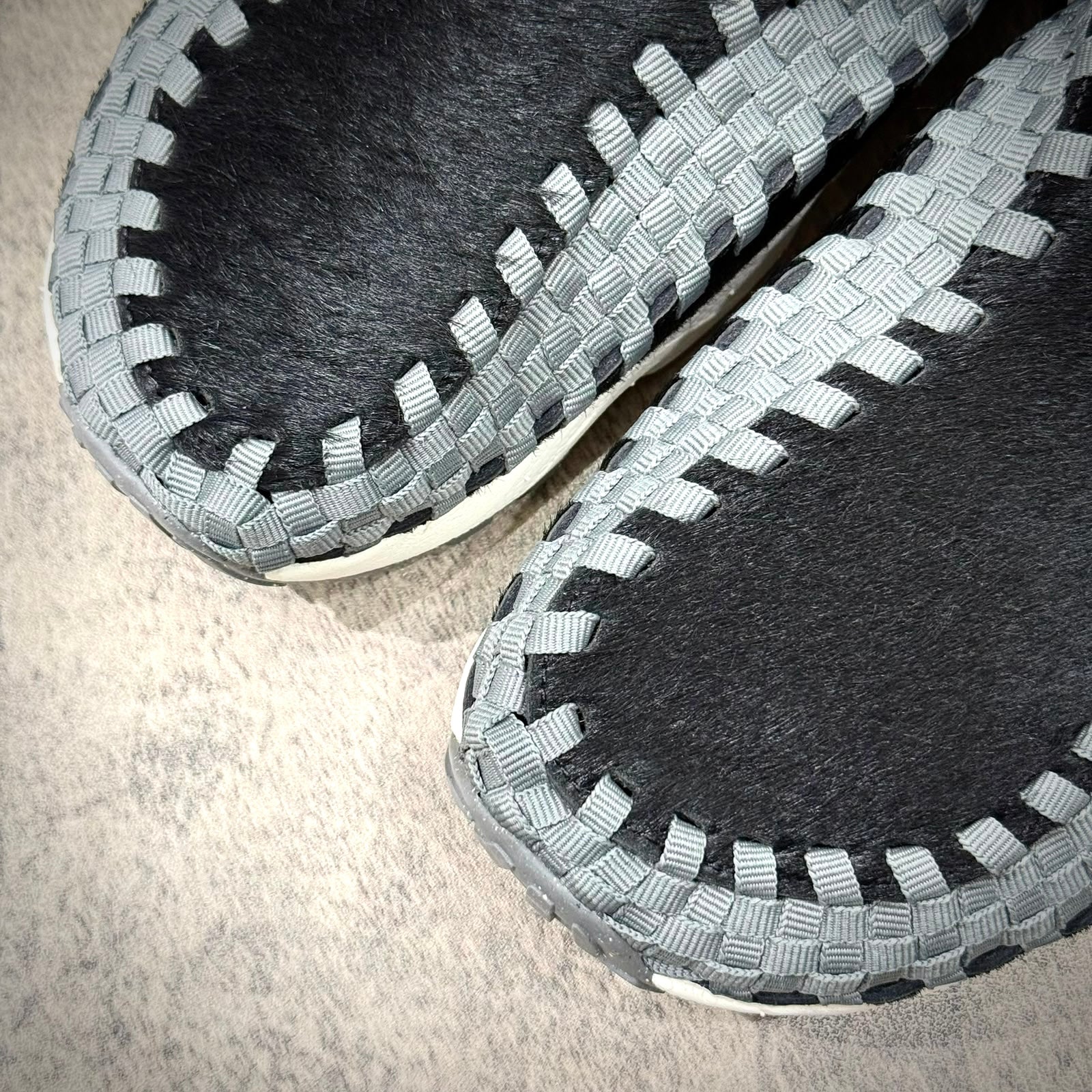 Close-up of Nike Air Footscape Woven Black Smoke Grey shoes showcasing intricate woven design and color details.