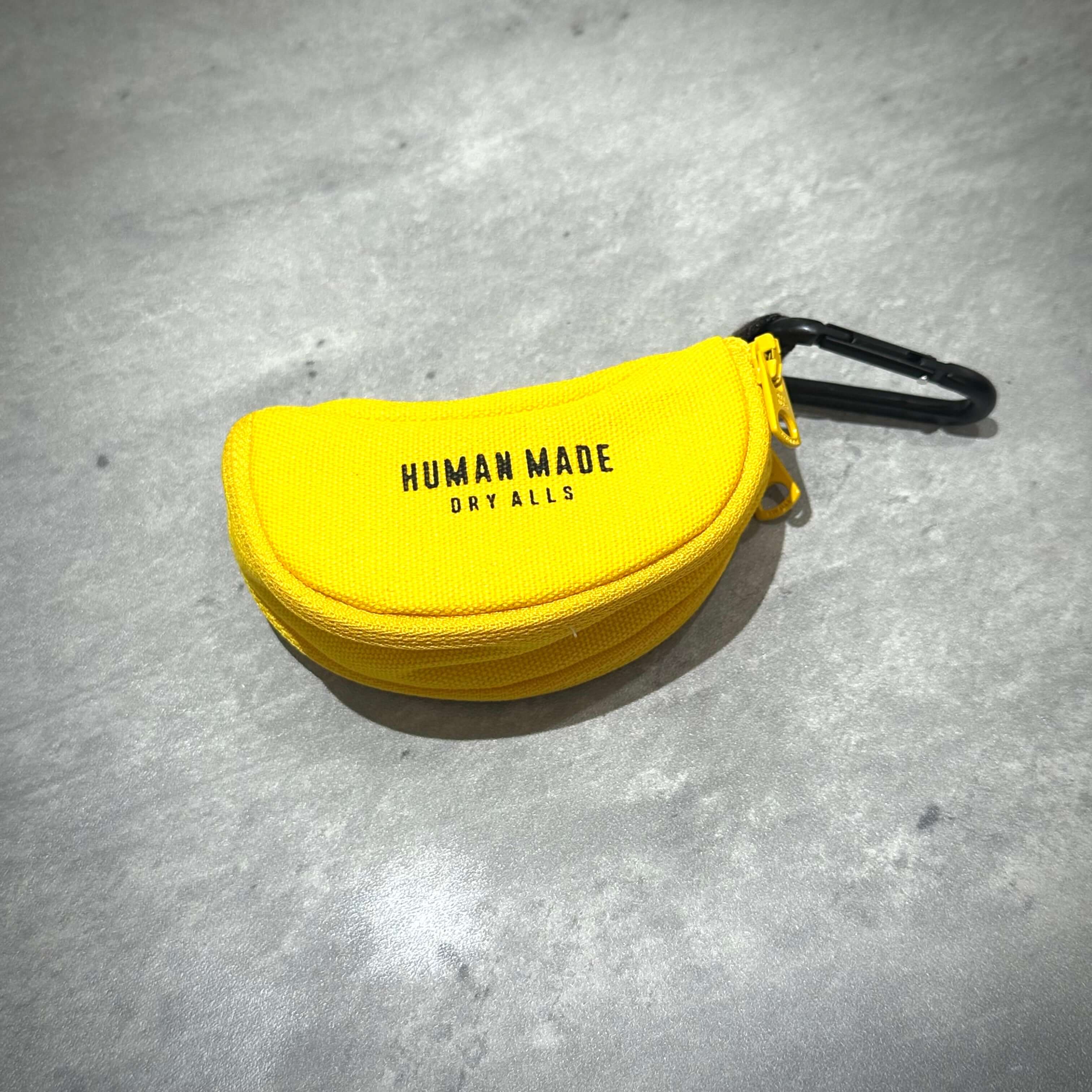 Human Made Banana Pouch in yellow, featuring a carabiner and logo, showcasing a unique design.