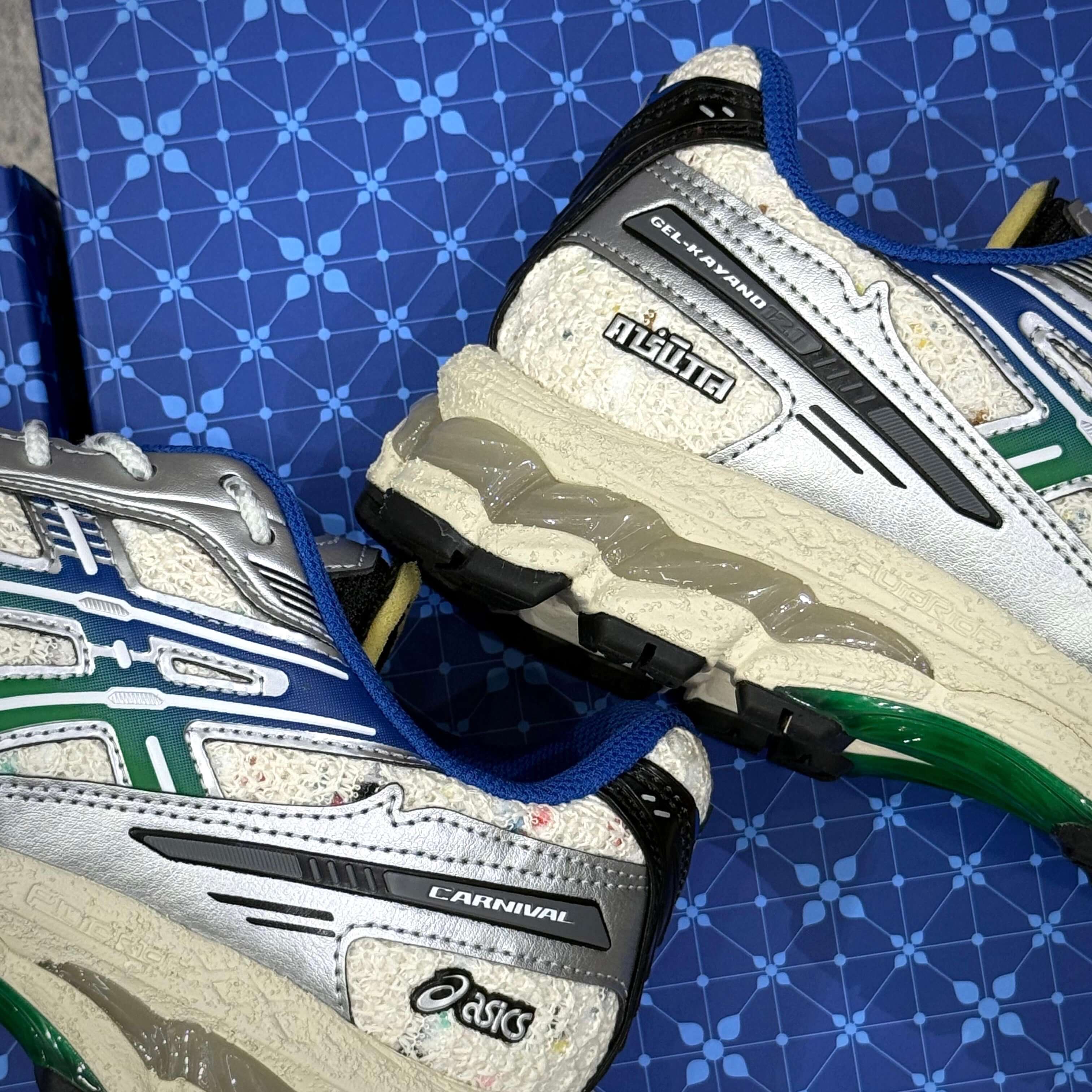 Carnival x Asics Gel Kayano 12.1 PHRA NAKHON sneaker with unique design and colors on a blue patterned background.