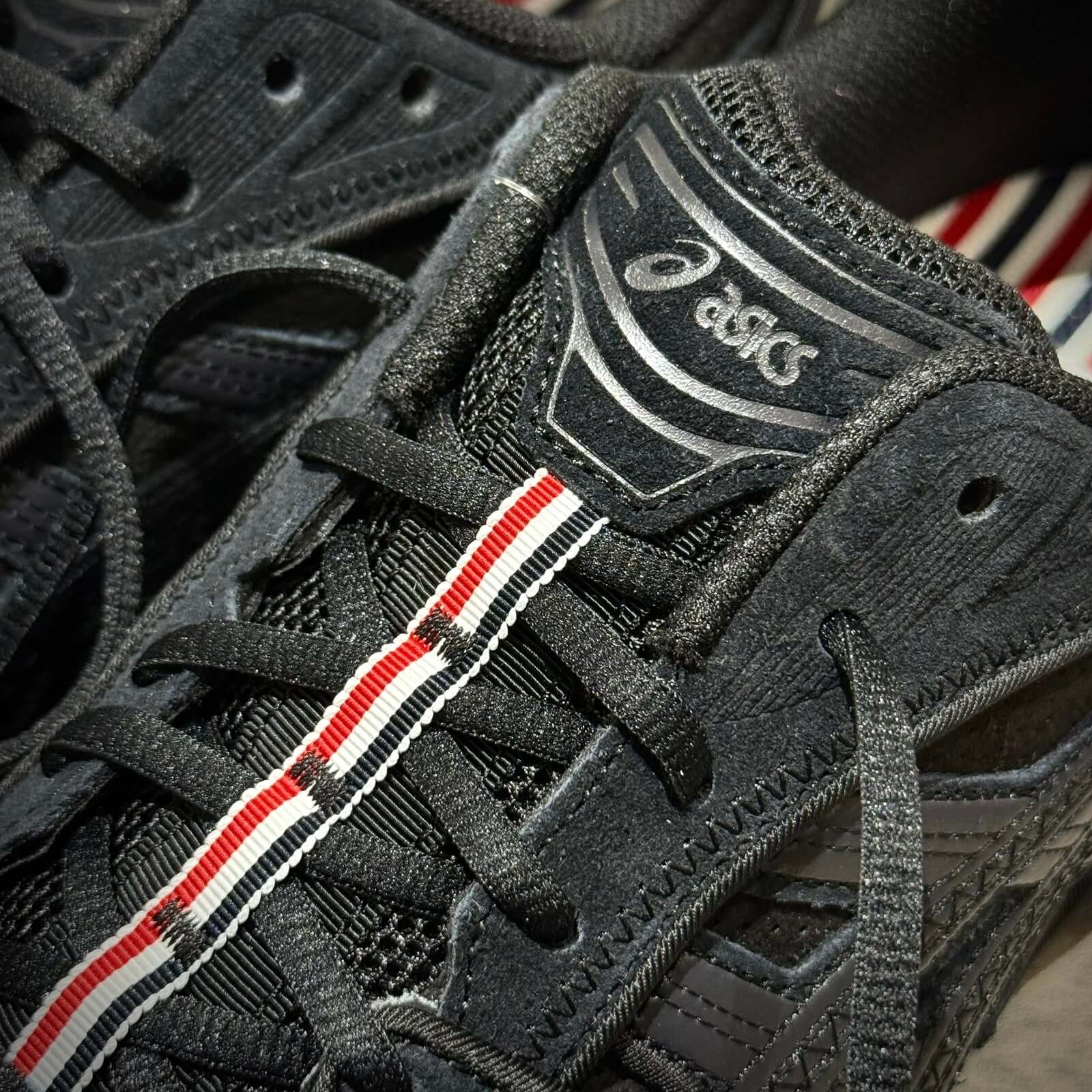 Close-up of Thom Browne x Asics Gel-Kayano 14 - Black sneaker detailing with laces and logo.