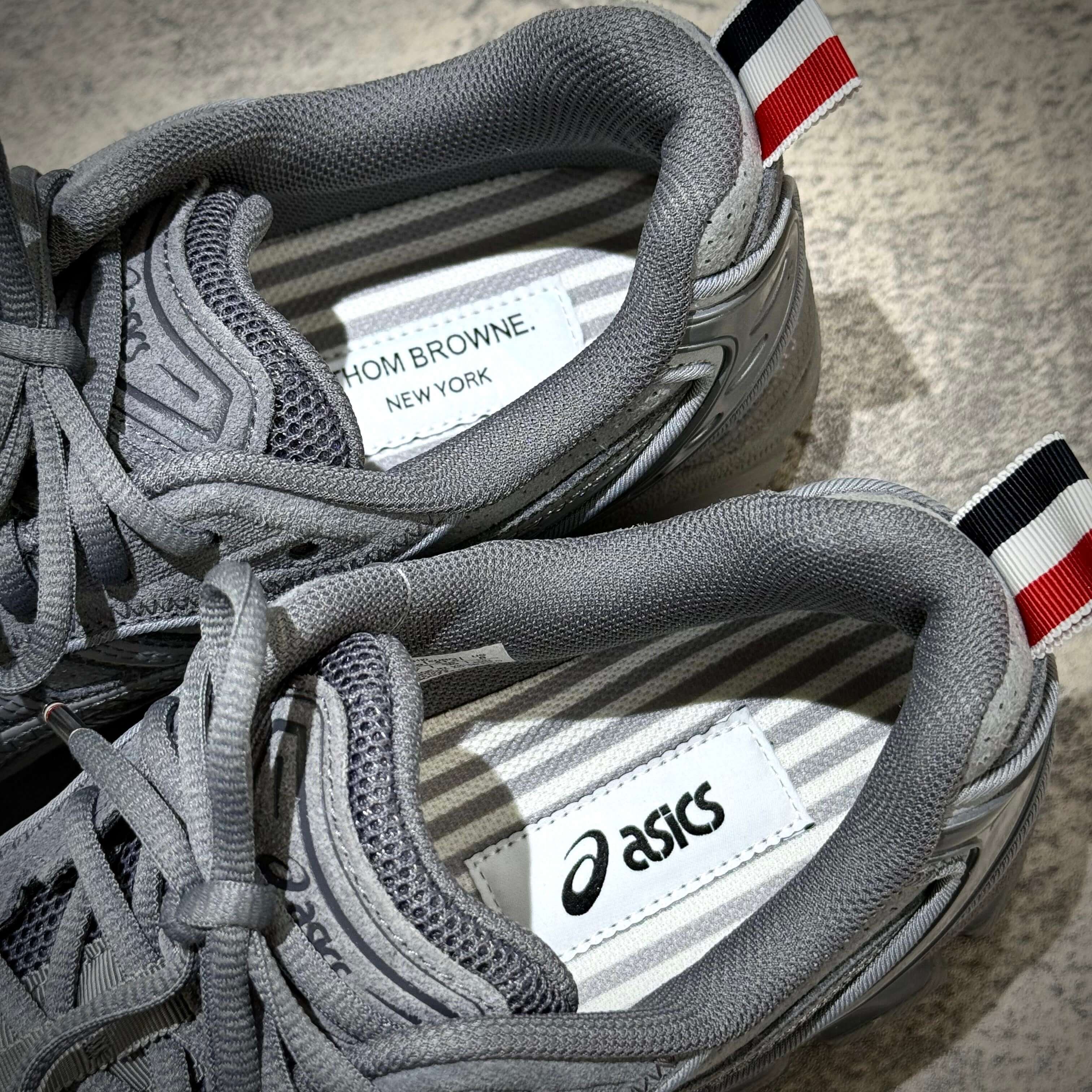 Thom Browne x Asics Gel-Kayano 14 in grey, showing the interior labels with 'Thom Browne. New York' and 'Asics' tags.