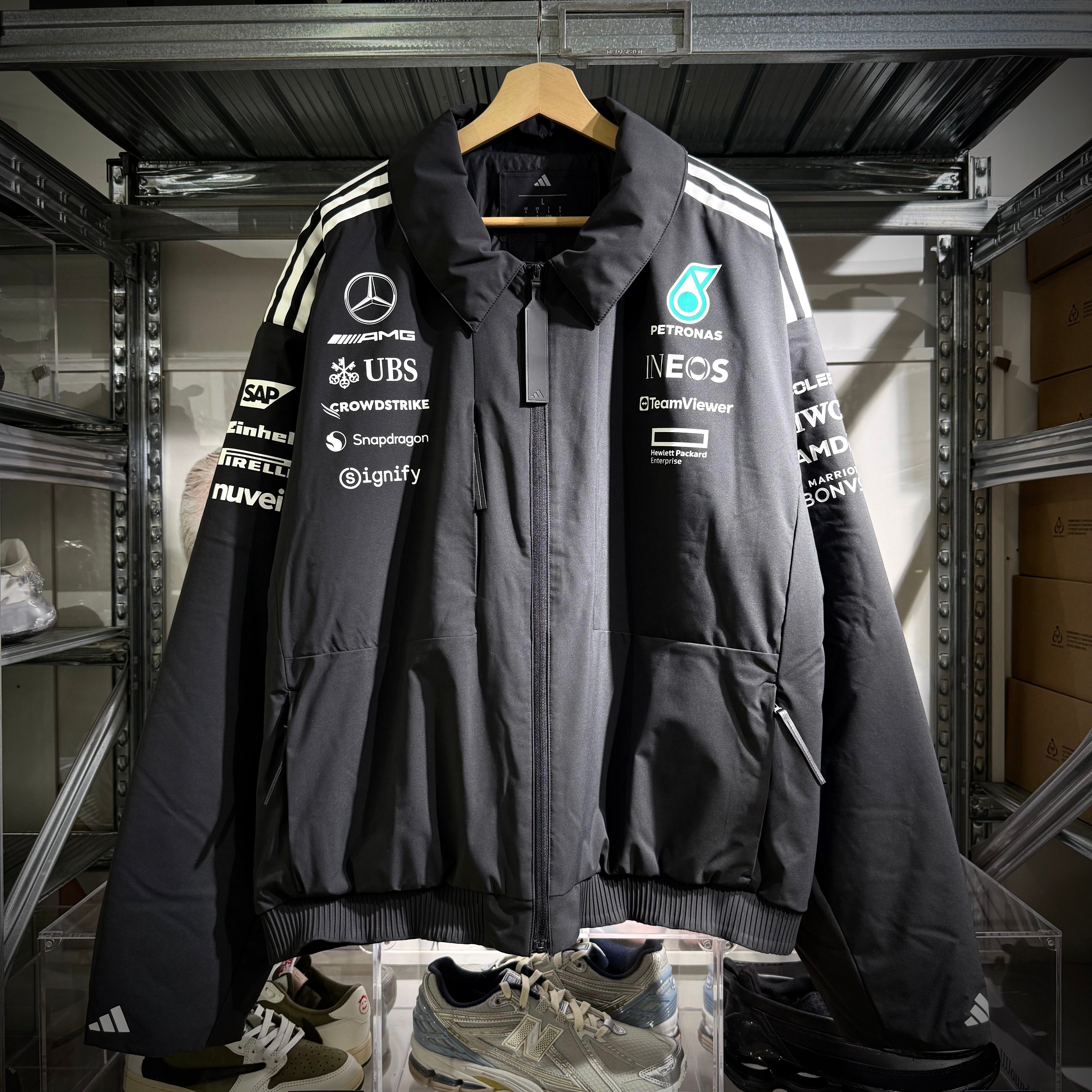 Adidas x Mercedes AMG Petronas 2025 F1 Team Jacket JX0748 displayed in a store, showcasing branding and team logos.