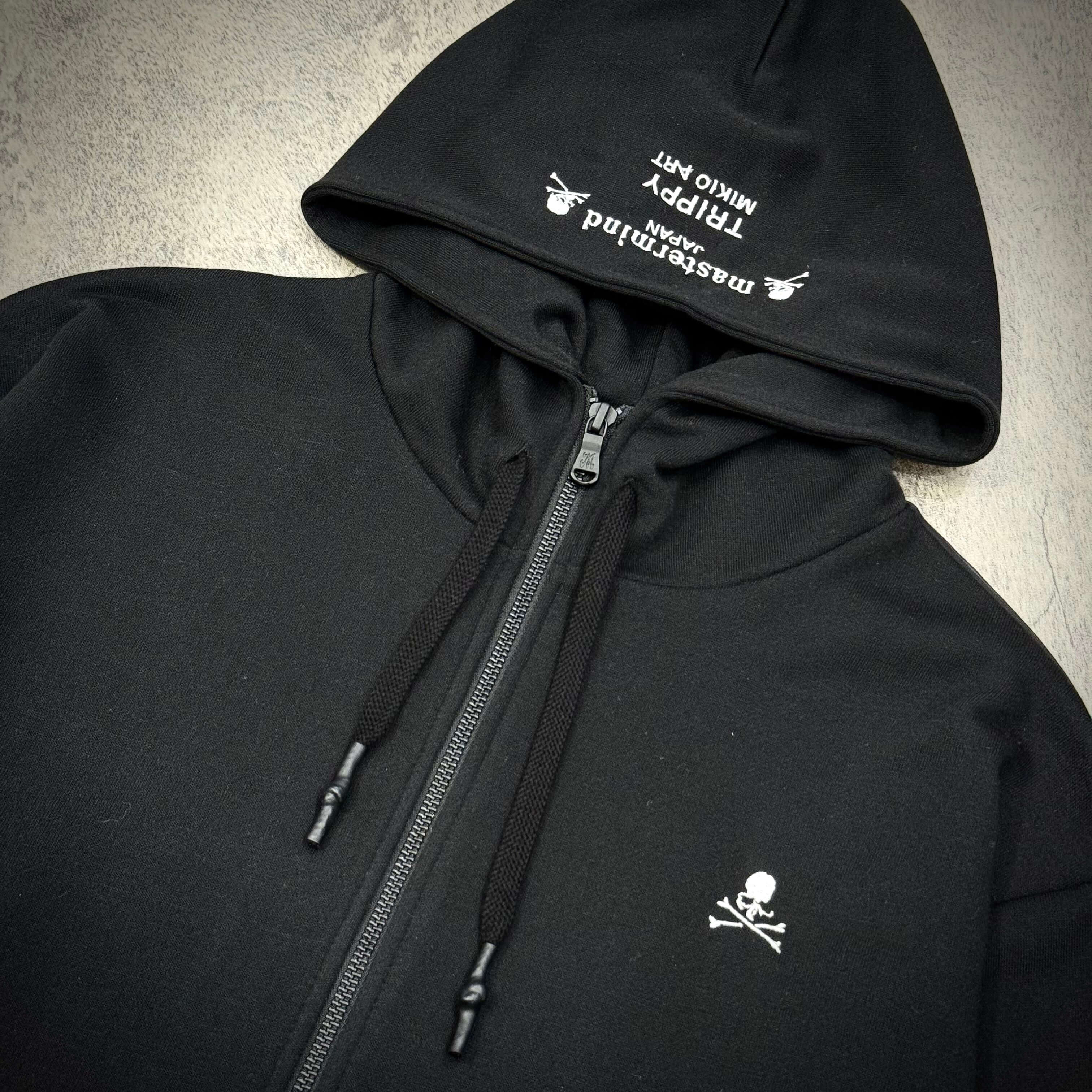 Mastermind Japan x Trippy Art Rock Star Zip Up hoodie featuring a black design with a skull logo and zippered front.