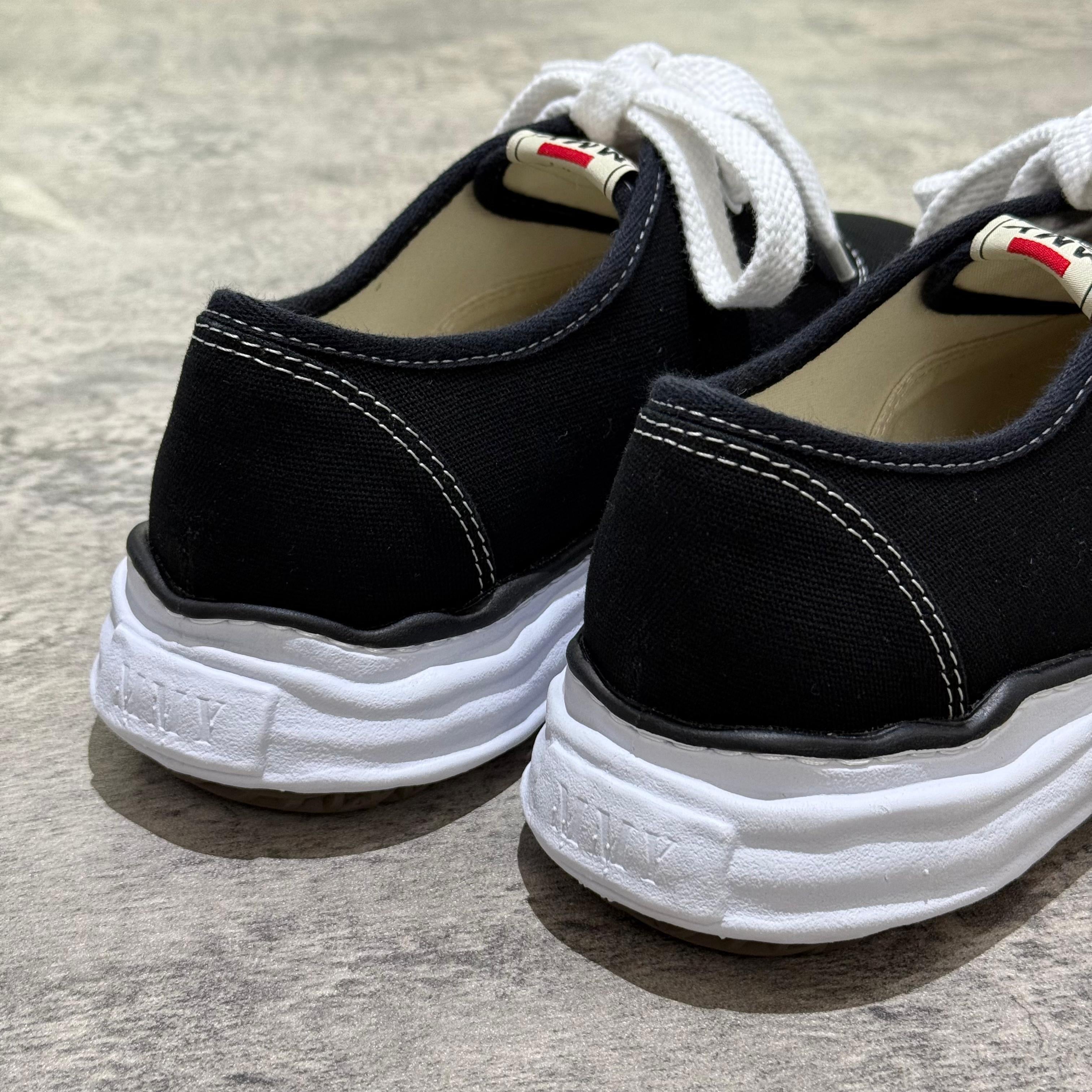 Close-up of the back of MMY BAKER OG Canvas shoes in black color with white laces and rubber sole.