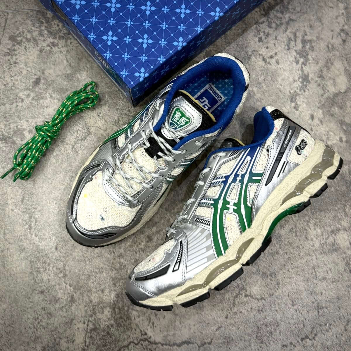 Carnival x Asics Gel Kayano 12.1 PHRA NAKHON sneakers featuring silver and green design with blue accents.