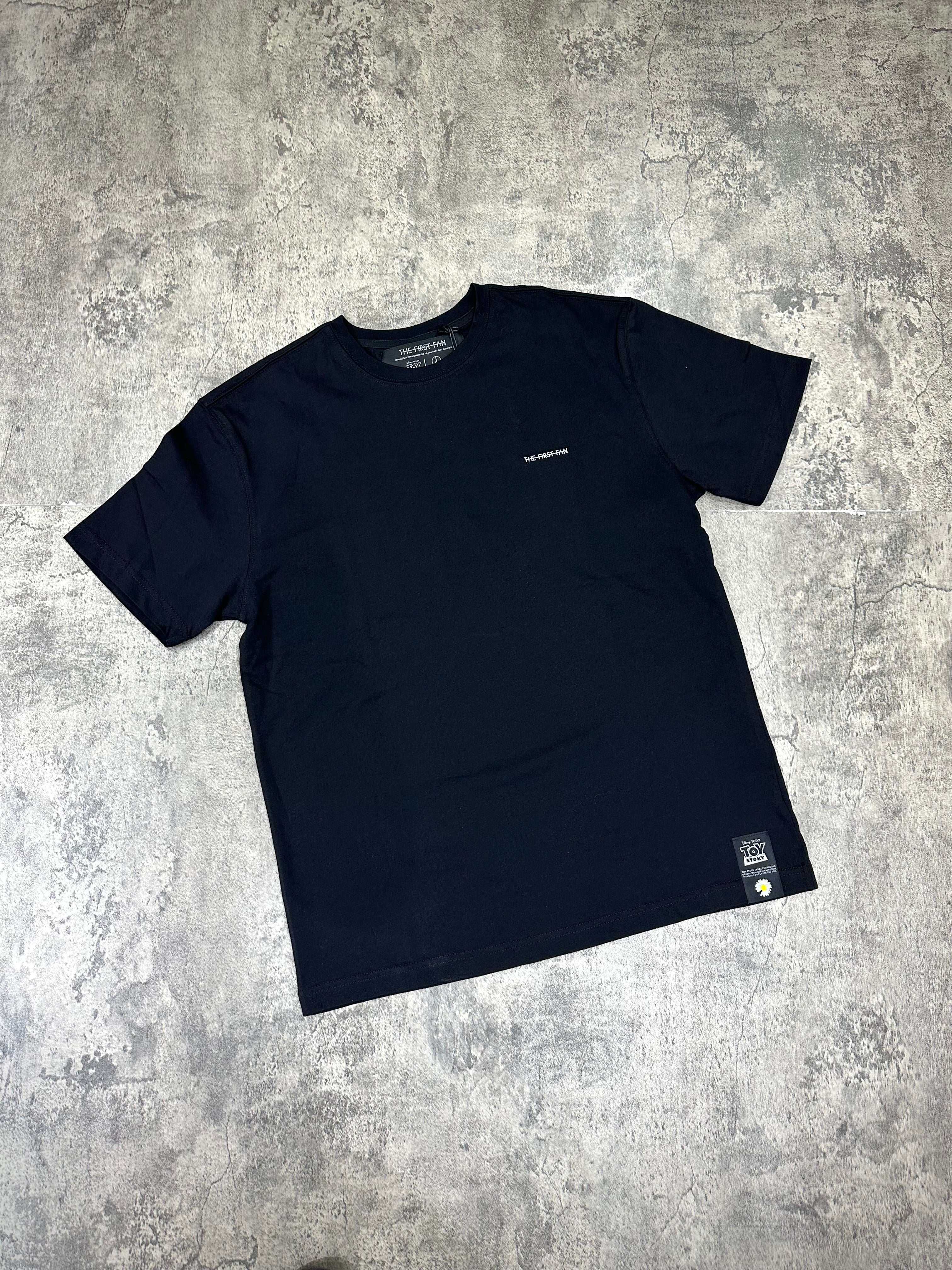 PEACEMINUSONE x Toy Story The First Fan - T-Shirt displayed on a textured background.