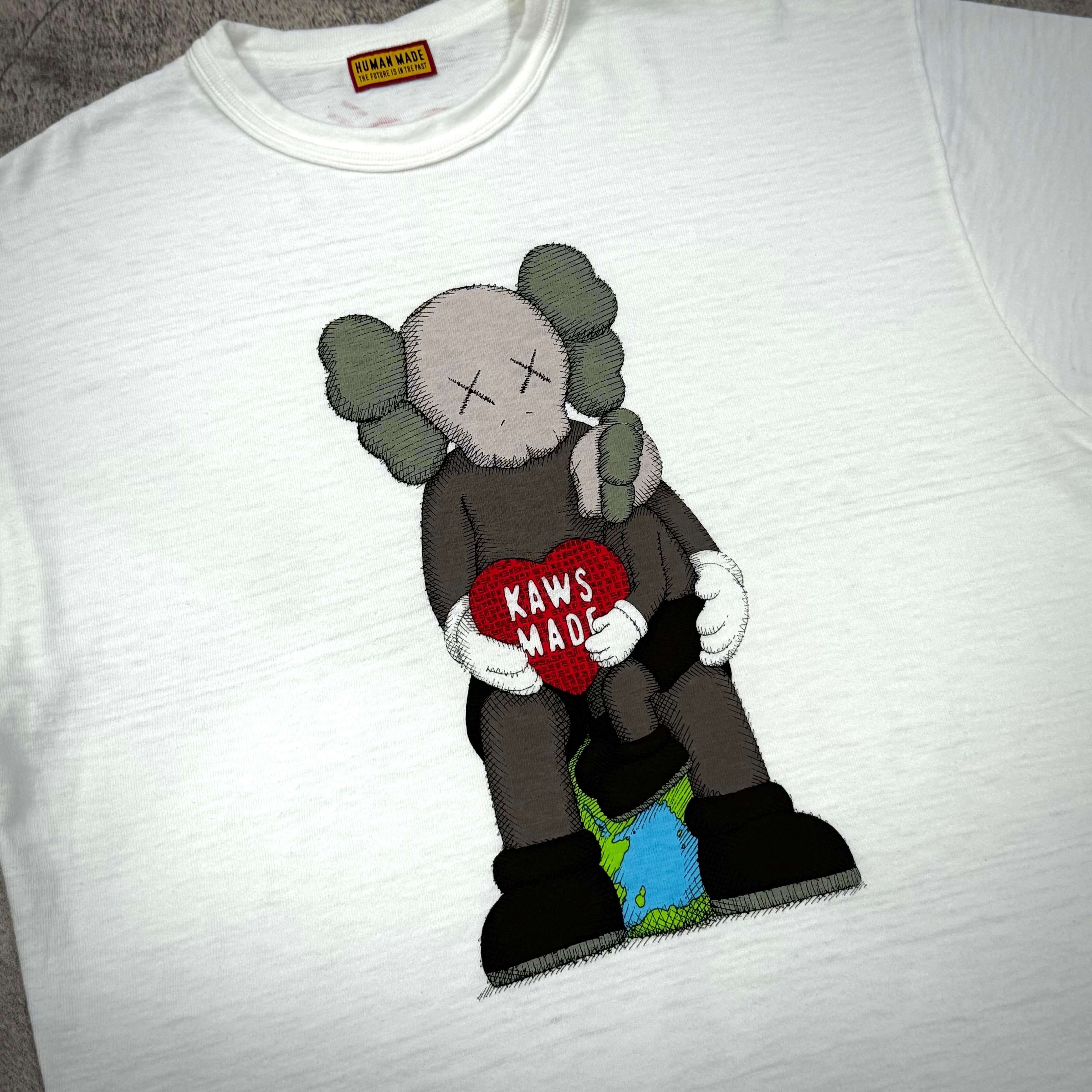 Human Made Bangkok Kaws Holiday logo tee featuring Kaws character holding heart with text 'KAWS MADE'.