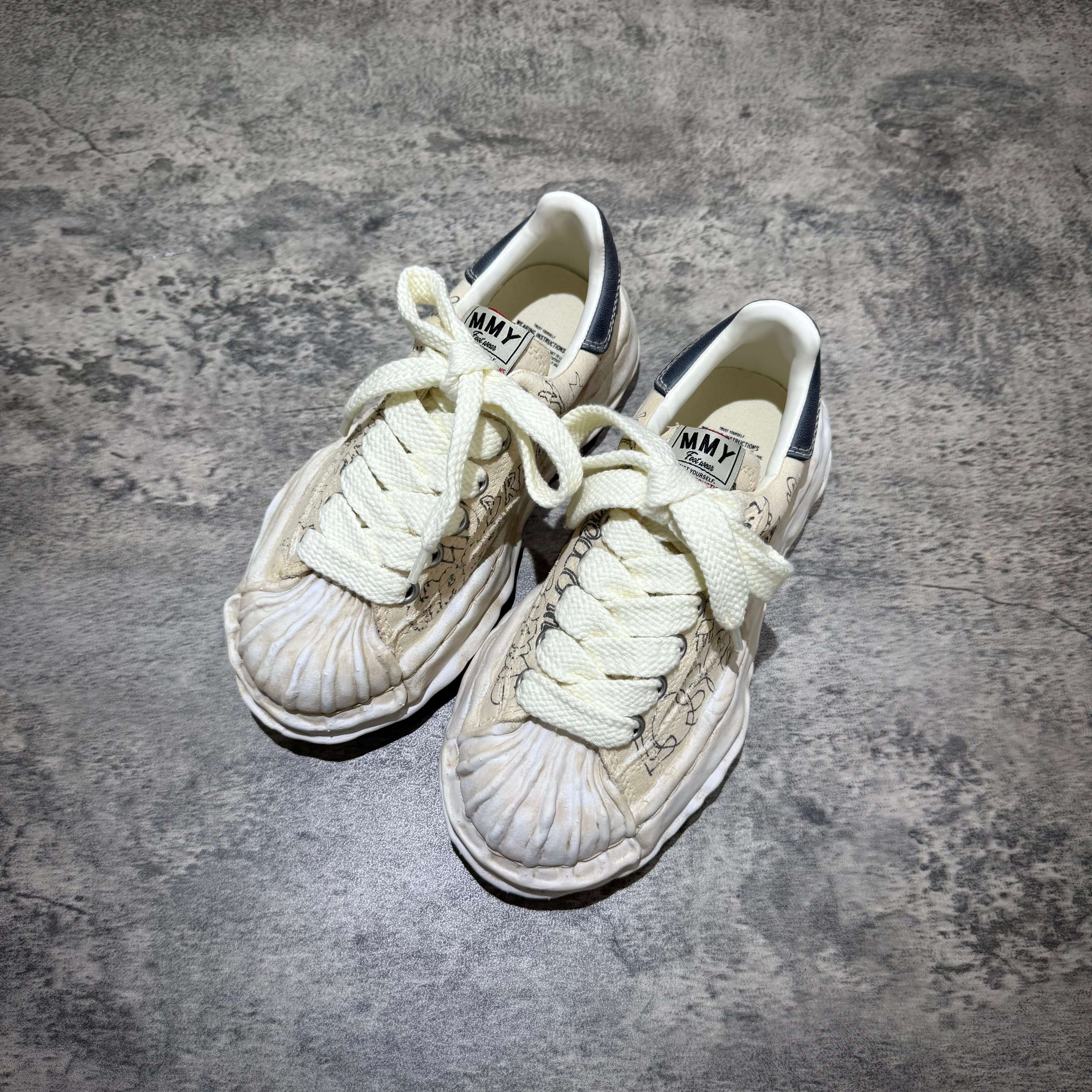 MMY BLAKEY Graffiti Printed Canvas Low sneakers with intricate design and yellow laces on textured background.