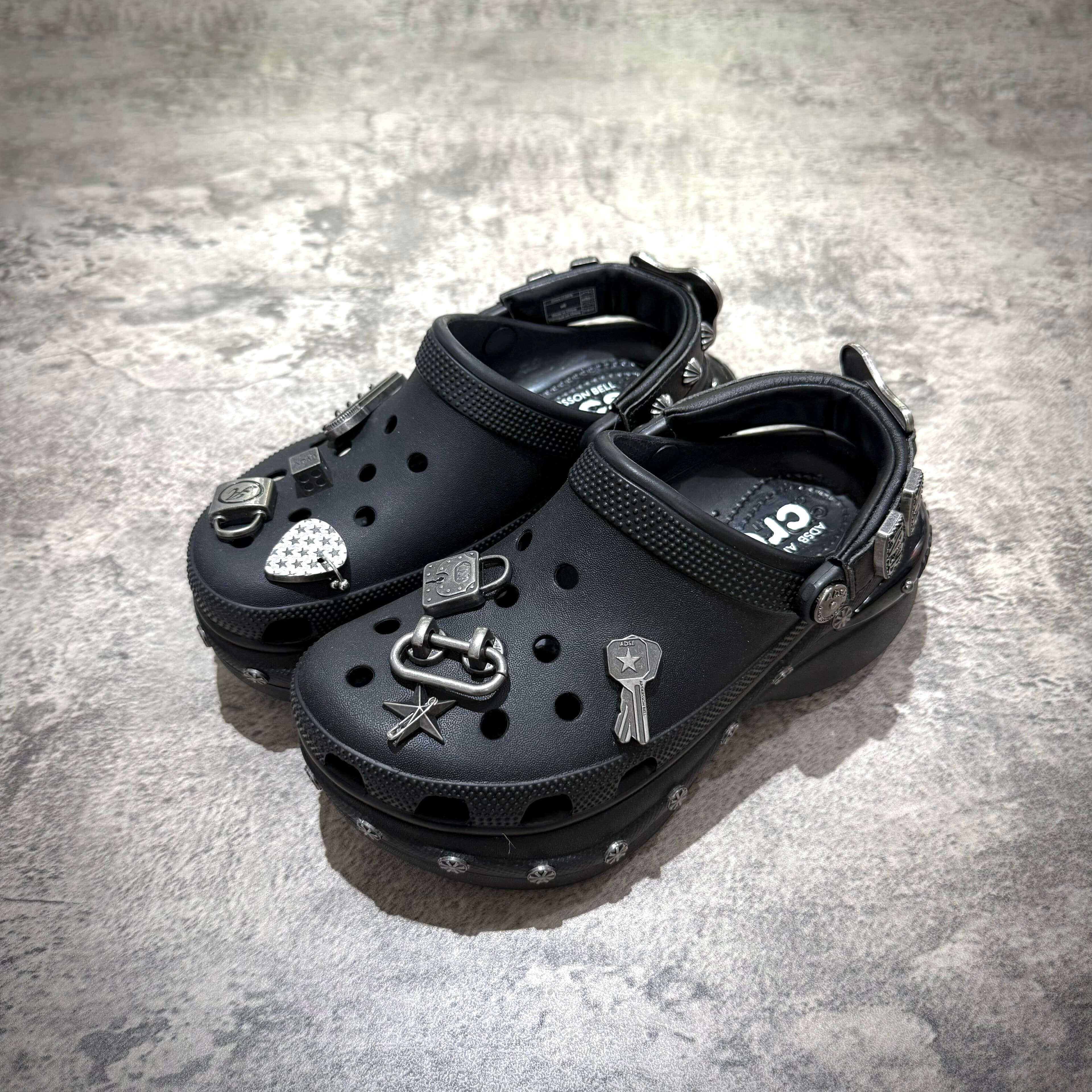 ANDERSSON BELL x Crocs Bae Clog in black with decorative charms on a textured surface.