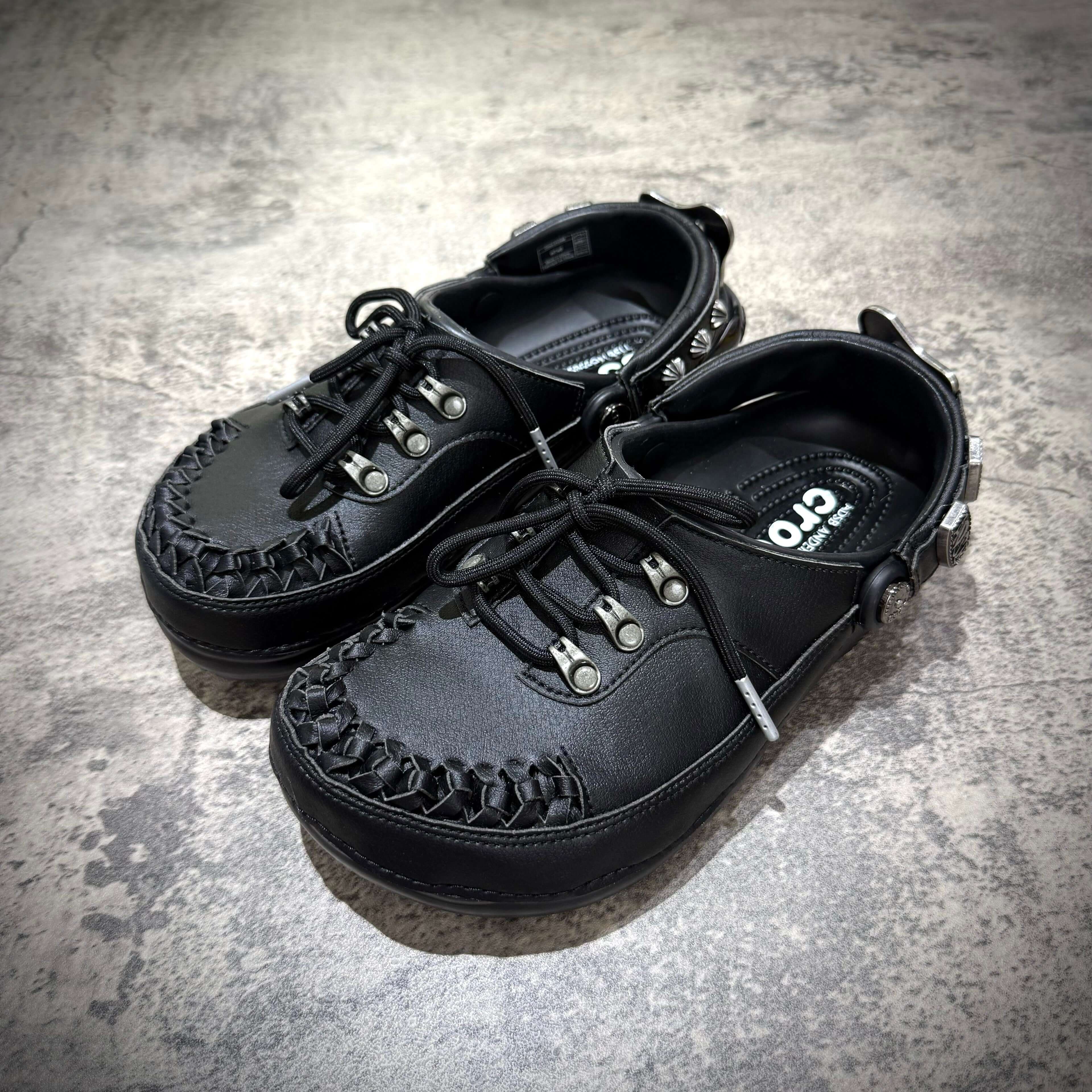 ANDERSSON BELL x Crocs Classic Clog featuring a stylish black design with braided detailing and lace-up closure.
