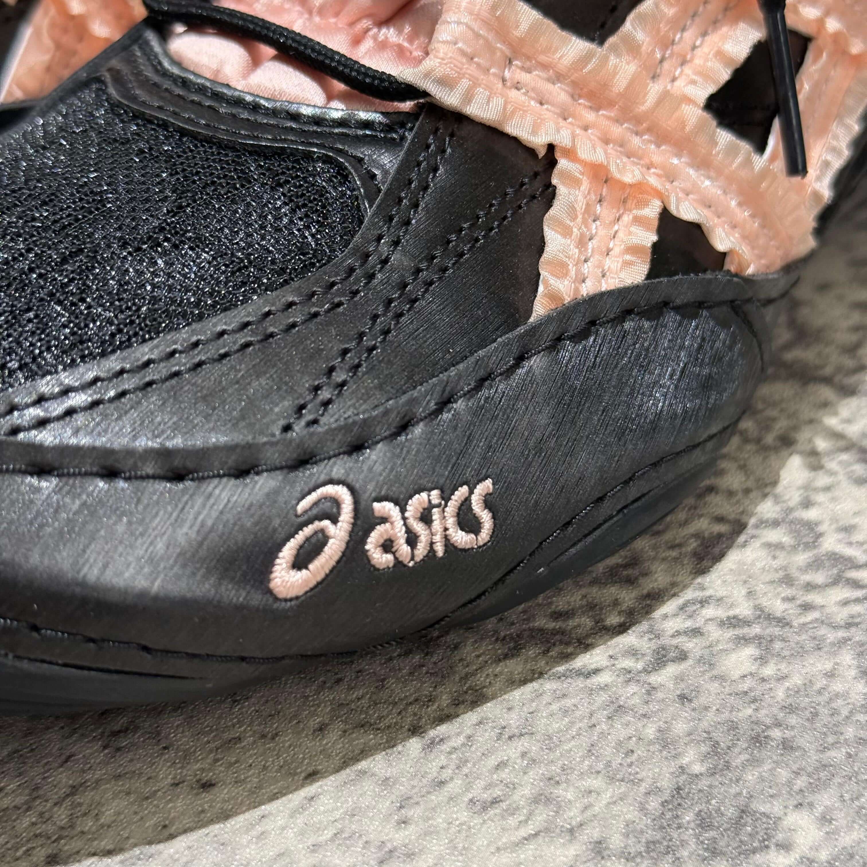 Close-up of Asics x Empty Behavior Hypersync in black and pink, showcasing logo detail and unique design elements.