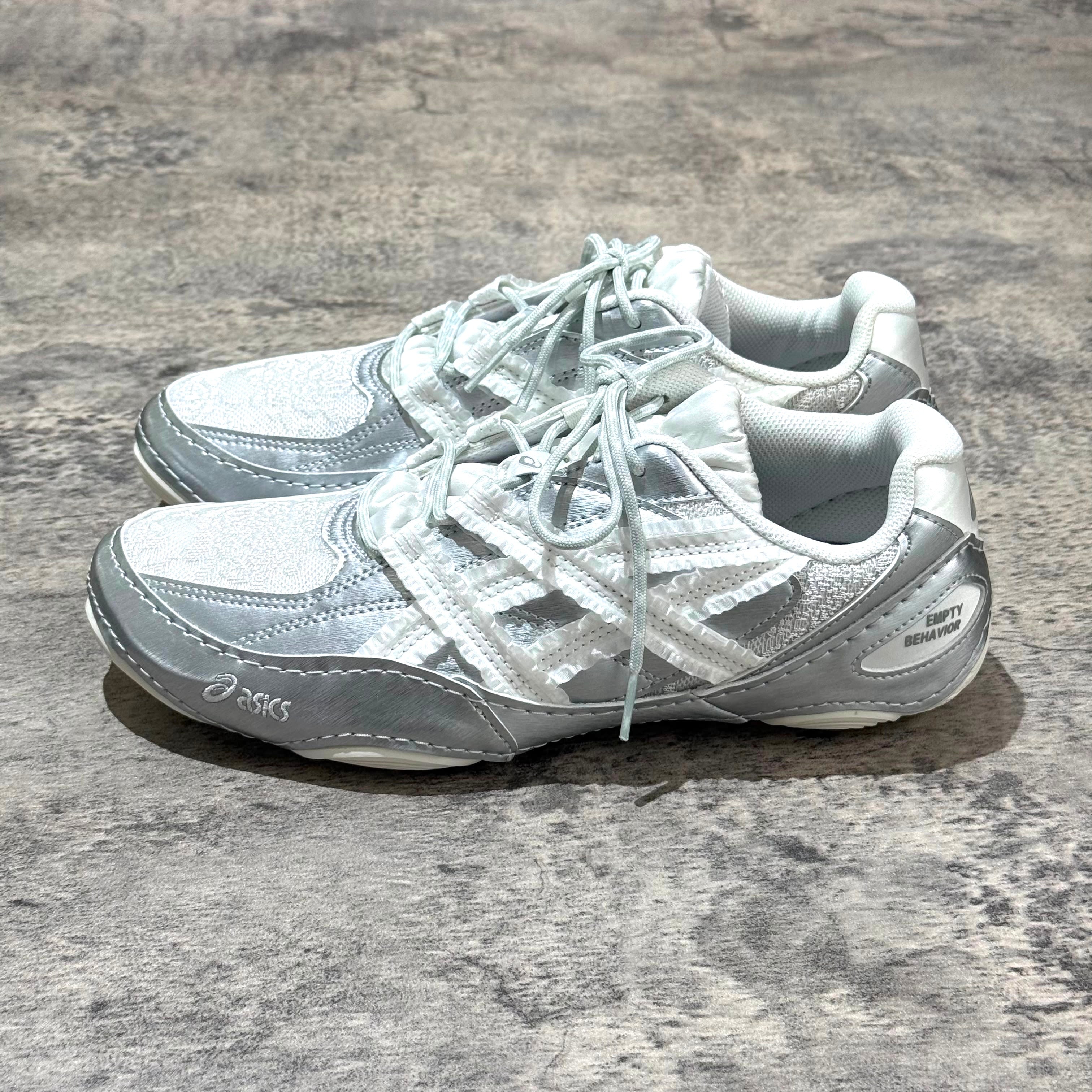 Asics x Empty Behavior Hypersync - Pure Silver White sneakers displayed from above on a textured surface.