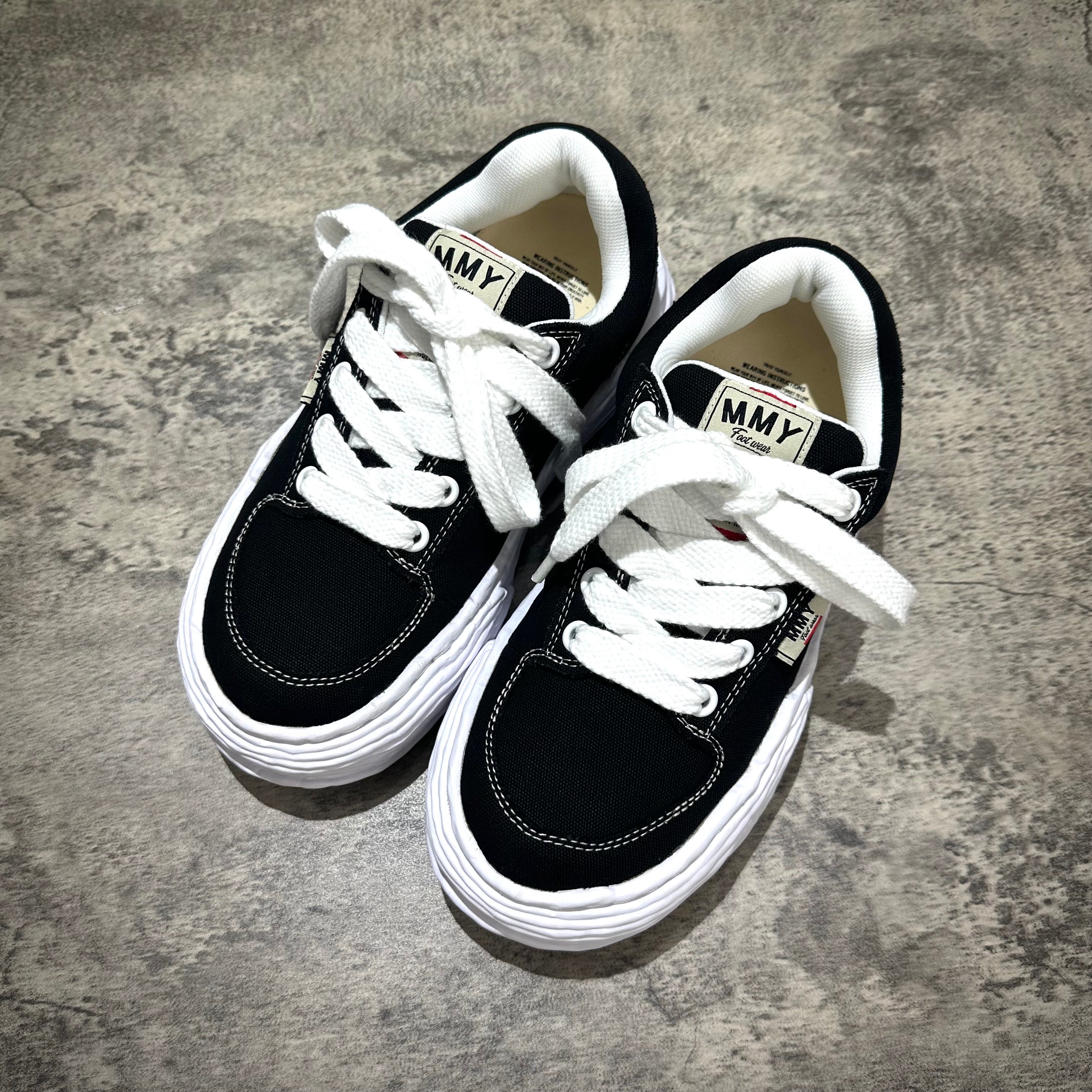 MMY Oliver Canvas Low - Black sneakers with white laces on a gray background.