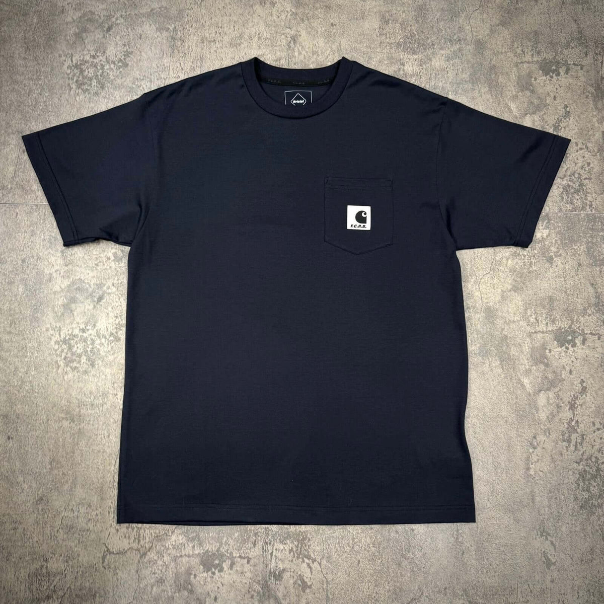 Carhartt WIP x F.C.Real Bristol Pocket Tee in dark navy color with chest pocket design.