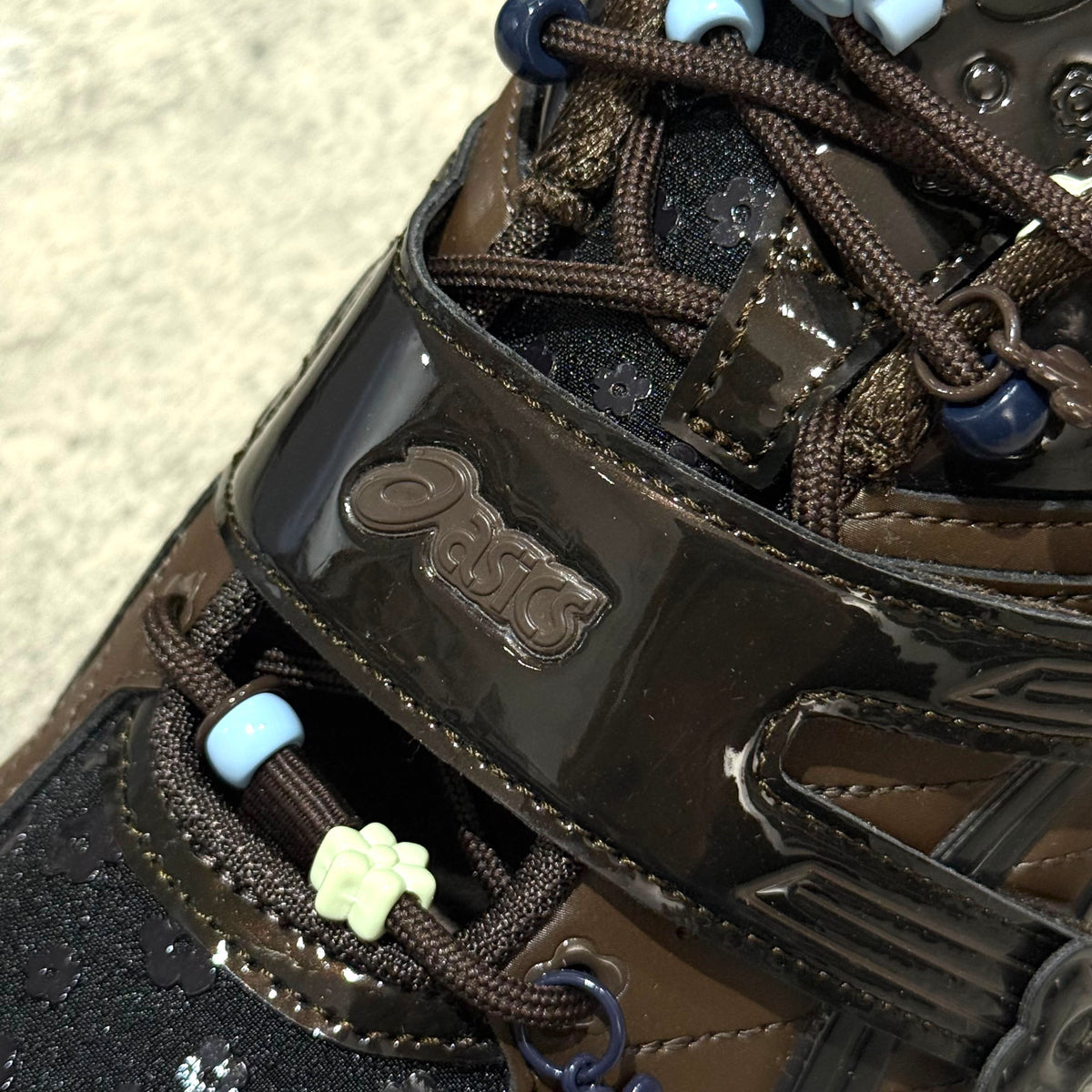 Close-up of Cecilie Bahnsen x Asics Gel-Kinetic FR - Black Coffee 1203B171-001 shoelace detailing and branding.