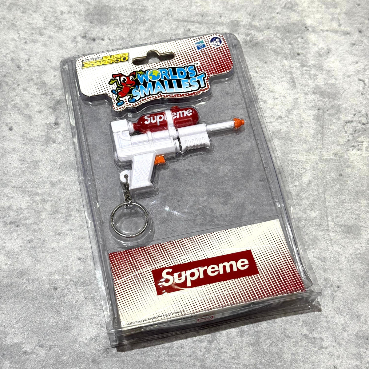 Supreme Super Soaker 50 Water Blaster Keychain in packaging, featuring a small water blaster design and Supreme branding.