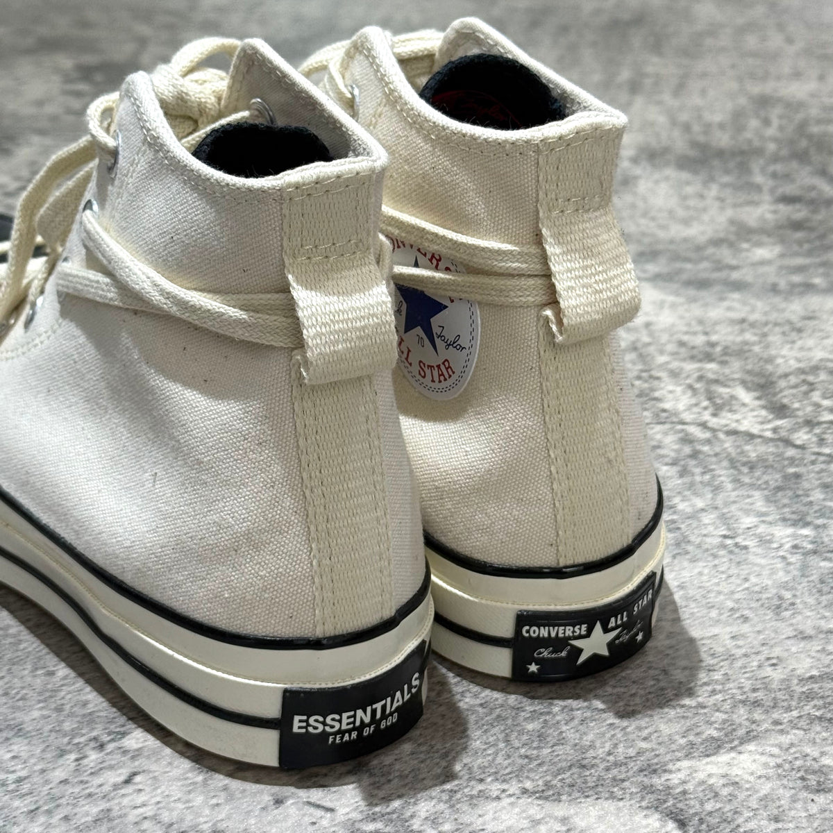 Fear Of God Essentials x Converse Chuck 70s Hi showing the back view of white canvas shoes with black branding