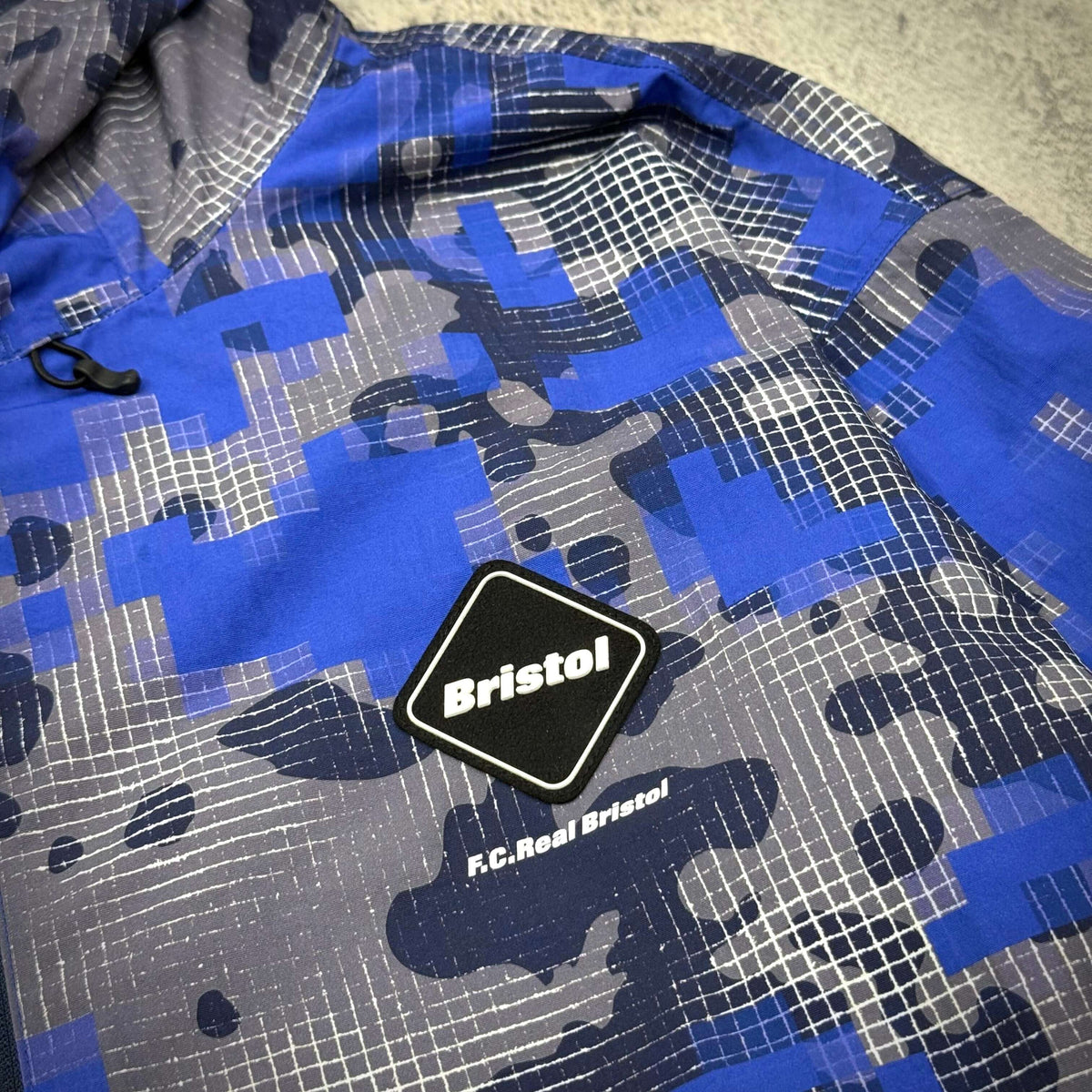 Fragment x F.C.Real Bristol Camouflage Nylon Blouson featuring blue camouflage pattern and logo patch