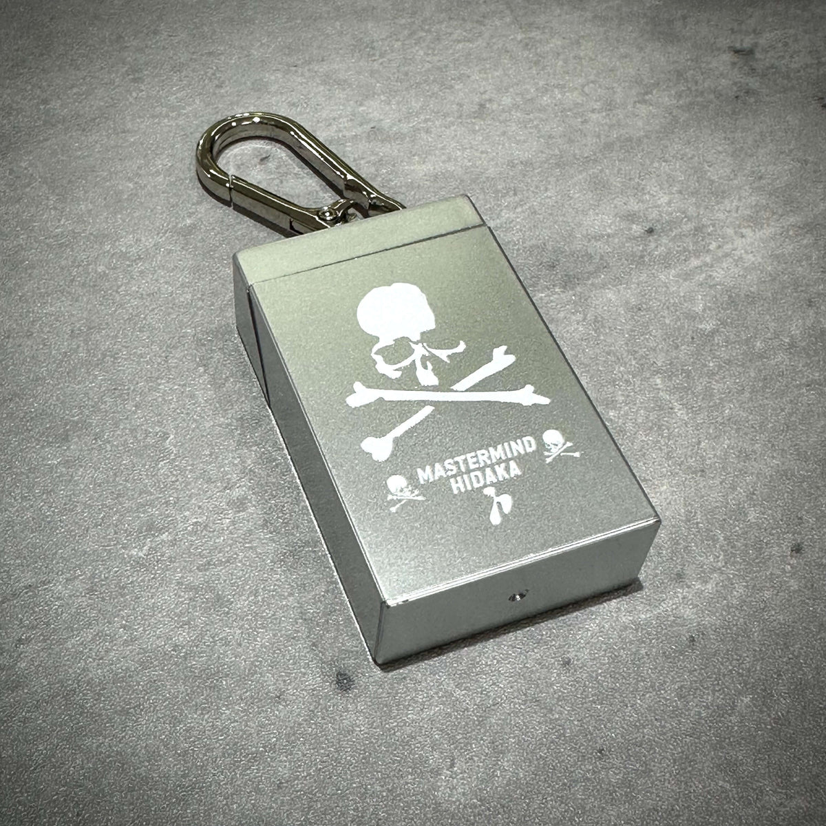 HIDAKA x mastermind JAPAN Portable Ashtray in silver with skull design and keychain attachment.