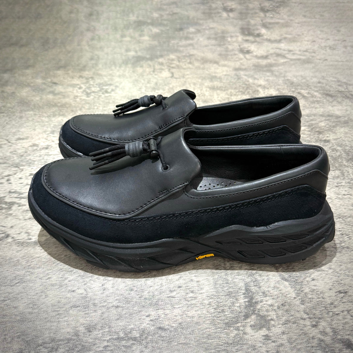 Hoka Speed Loafers - Black 1162170-BBLC displayed from the side on a textured surface.