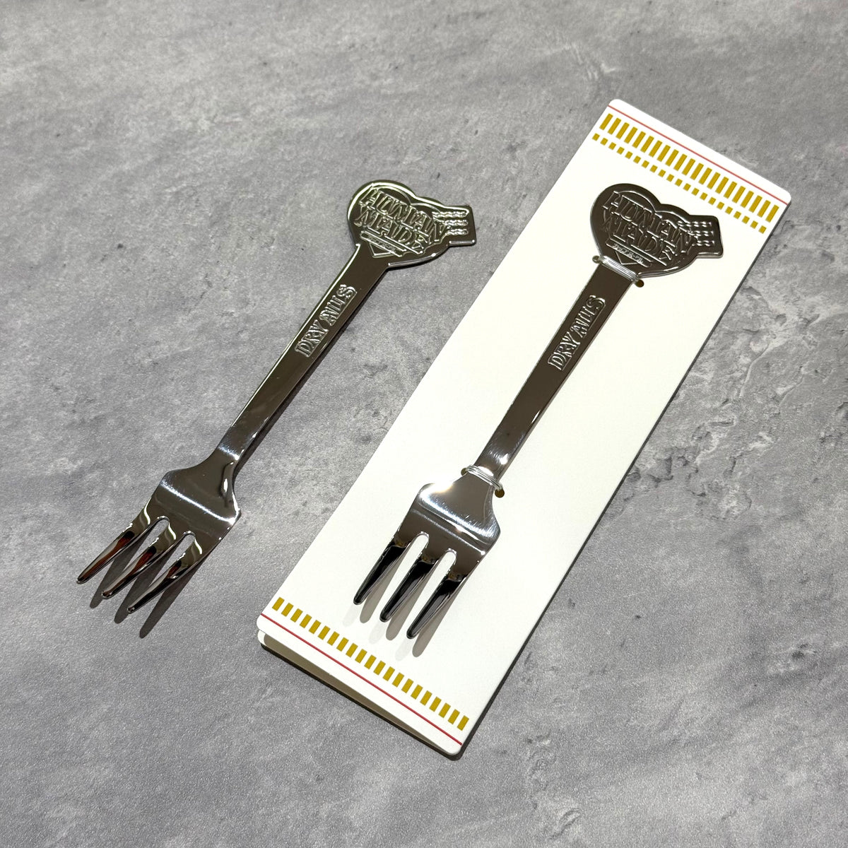 Human Made Cup Noodle Fork in stainless steel, displayed with packaging on a textured surface.