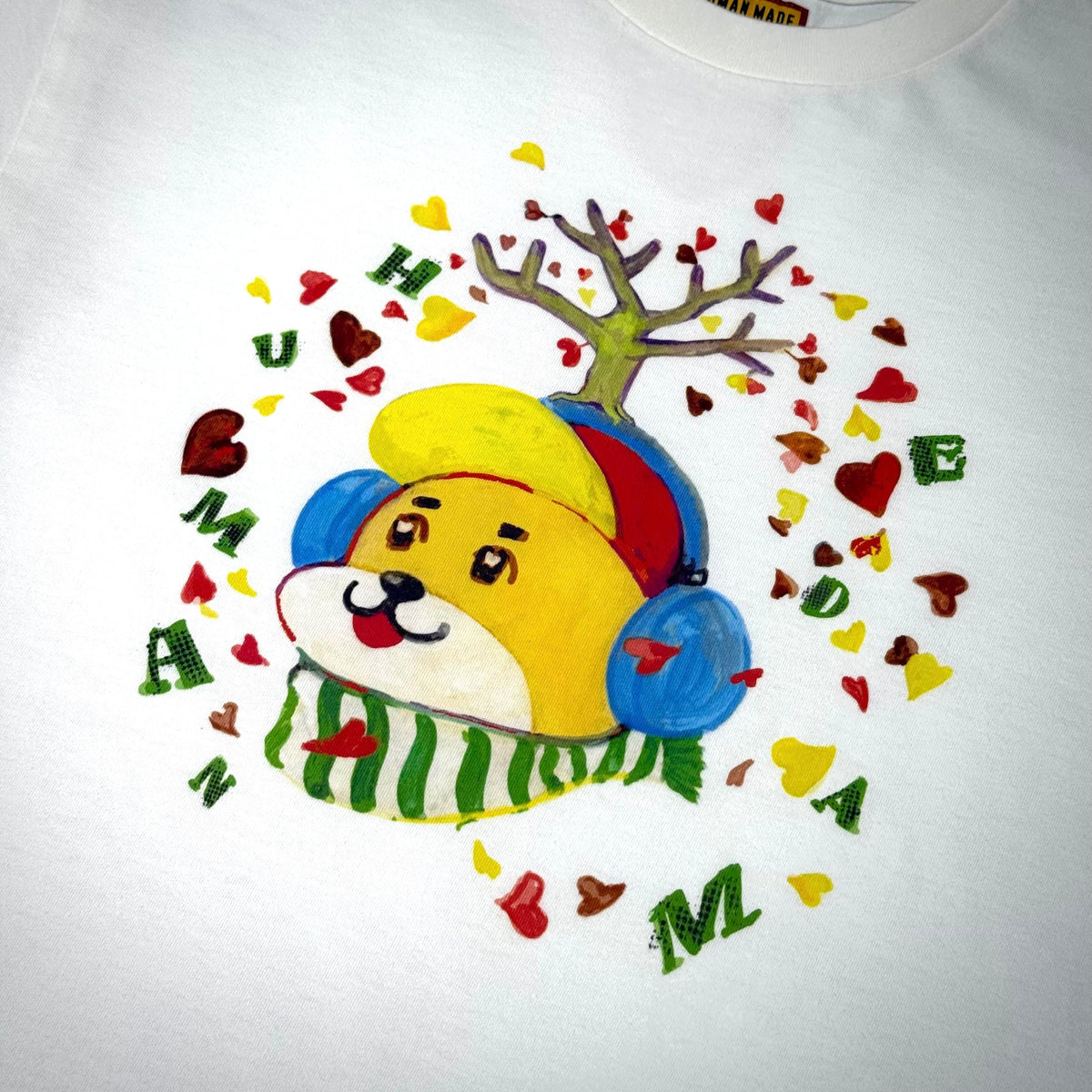 Colorful illustration of Human Made Keiko Sootome character wearing headphones and surrounded by hearts on a white tee.