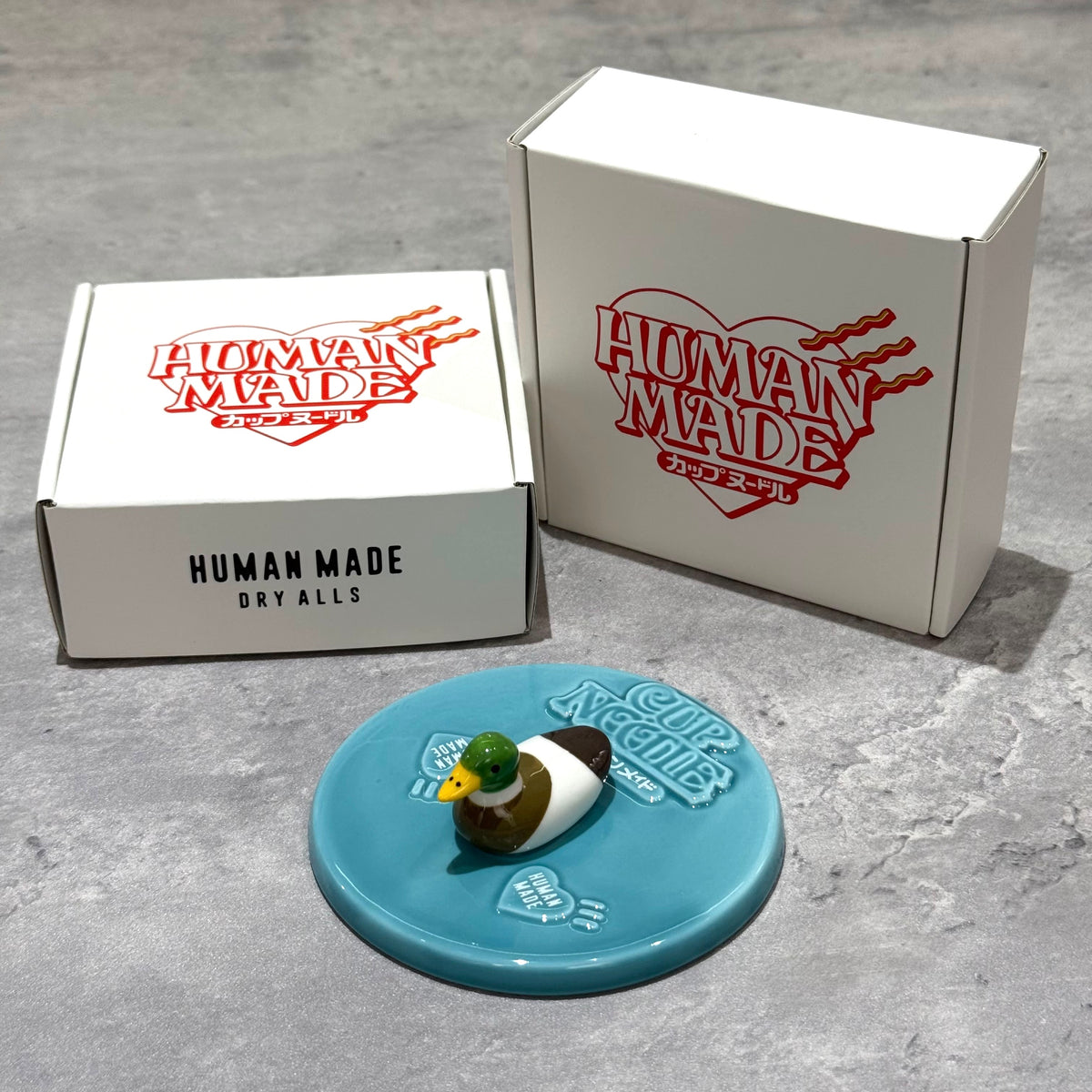 Human Made Lid Holder displayed with packaging, featuring a duck design on a blue base.